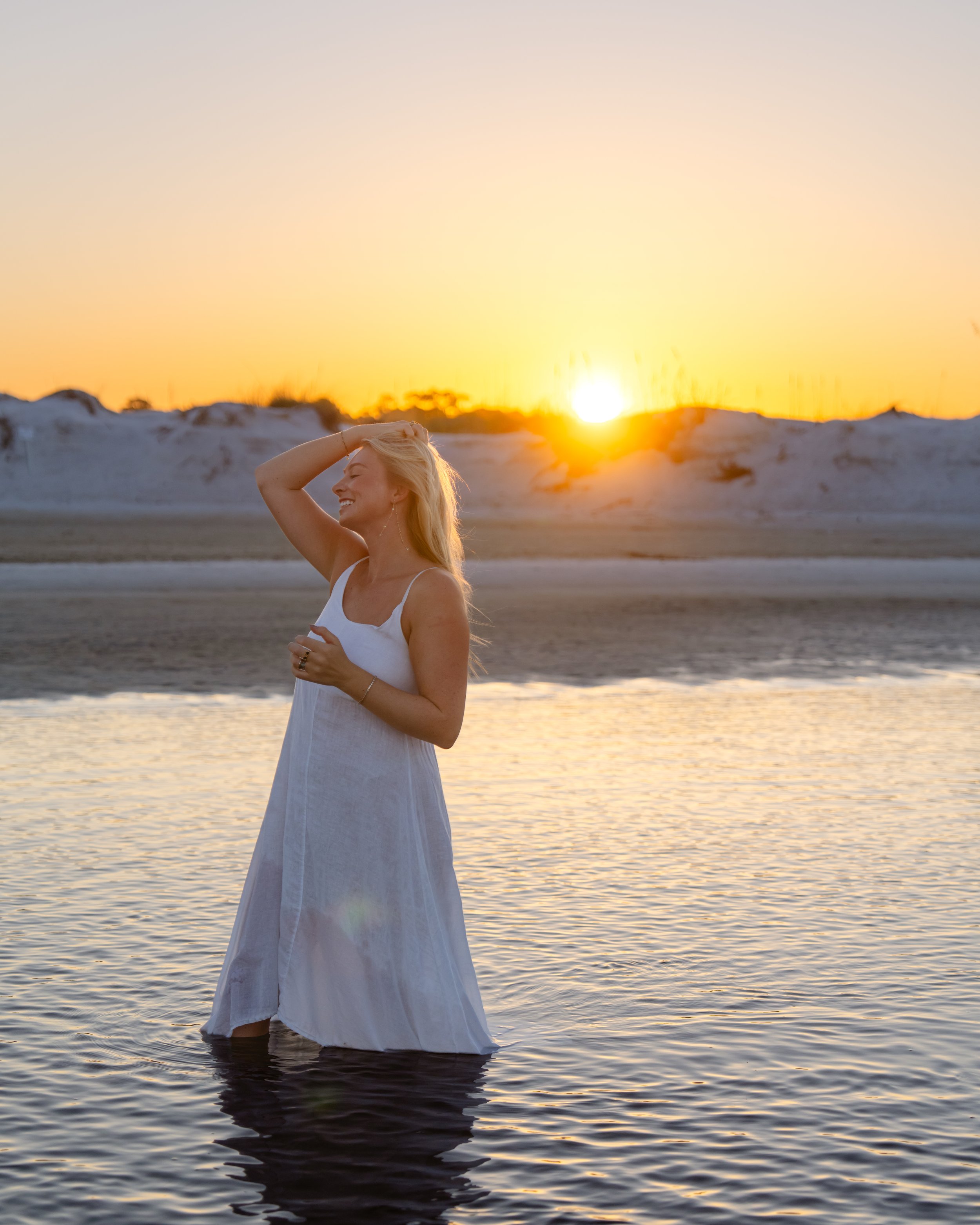 Portrait of a woman walking through a dune lake by the beach with the sunrise behind her. Grayton Beach Photographer. 30A Photographer