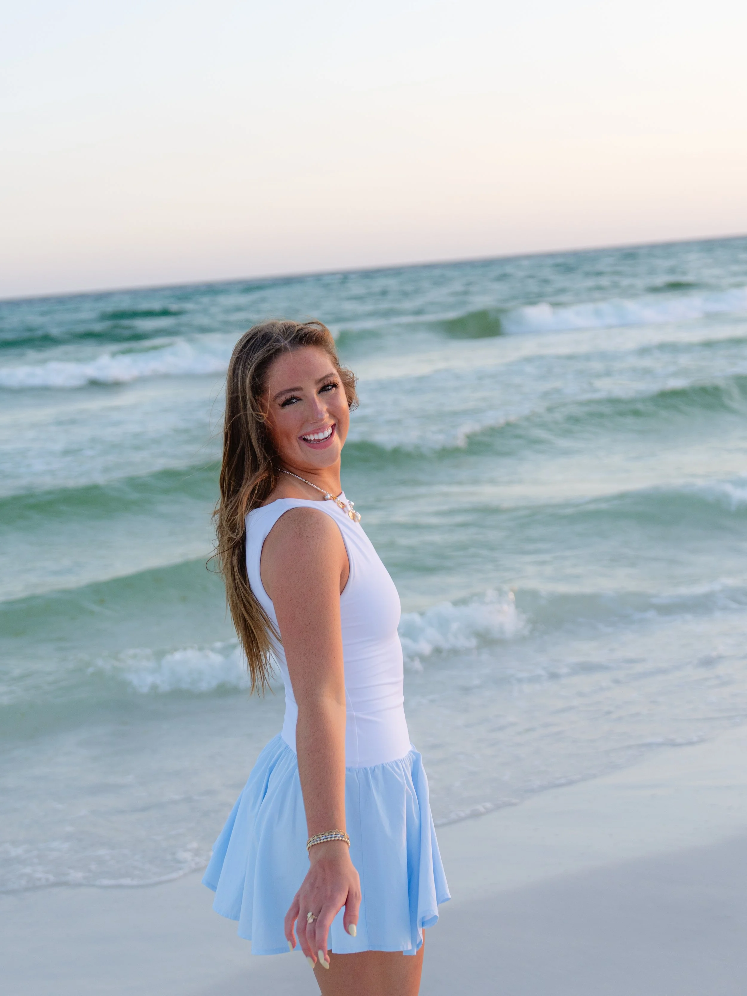 Woman smiling and looking over her shoulder walking on the beach smiling