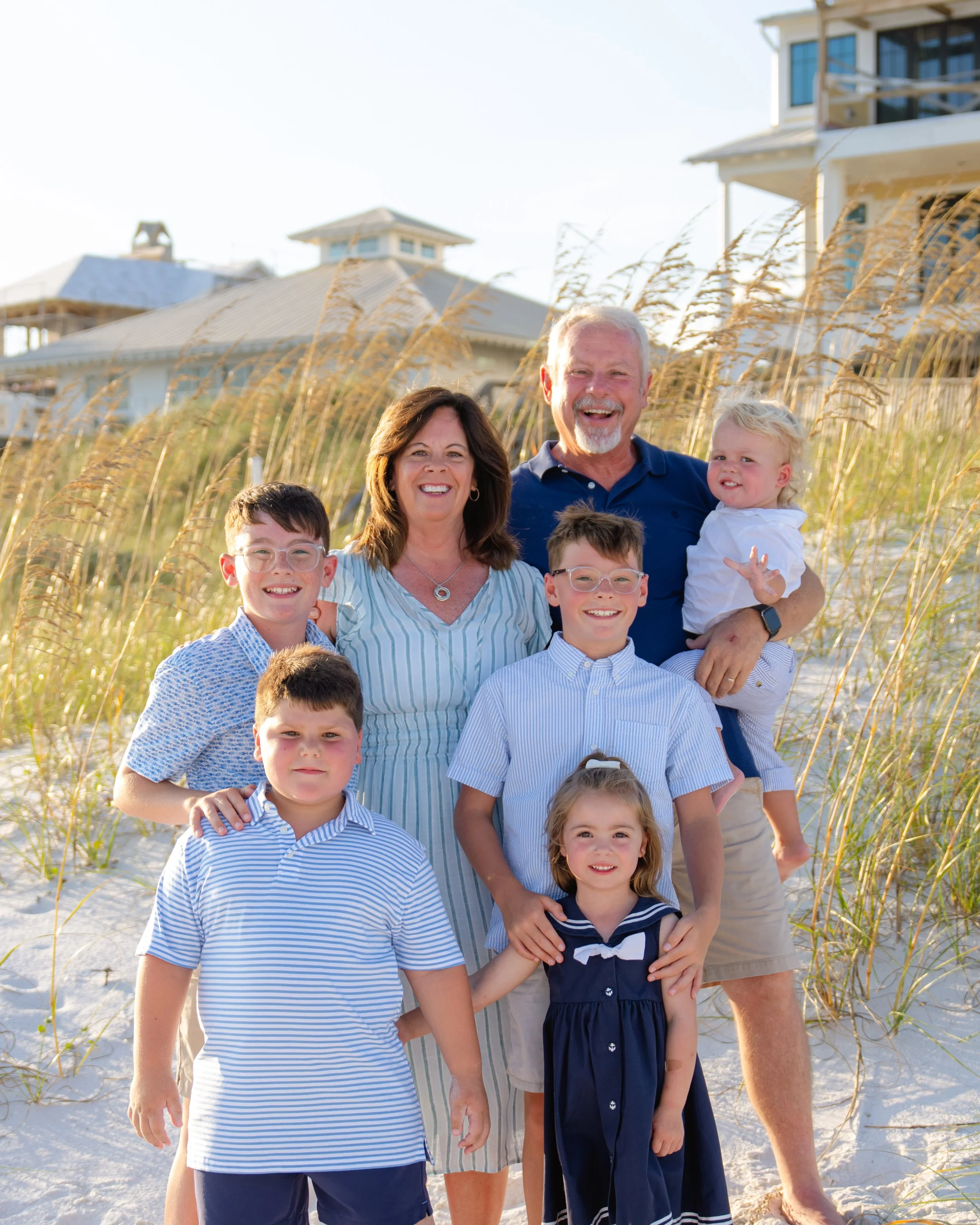Family of four walking on the beach, smiling, with the ocean in the background.