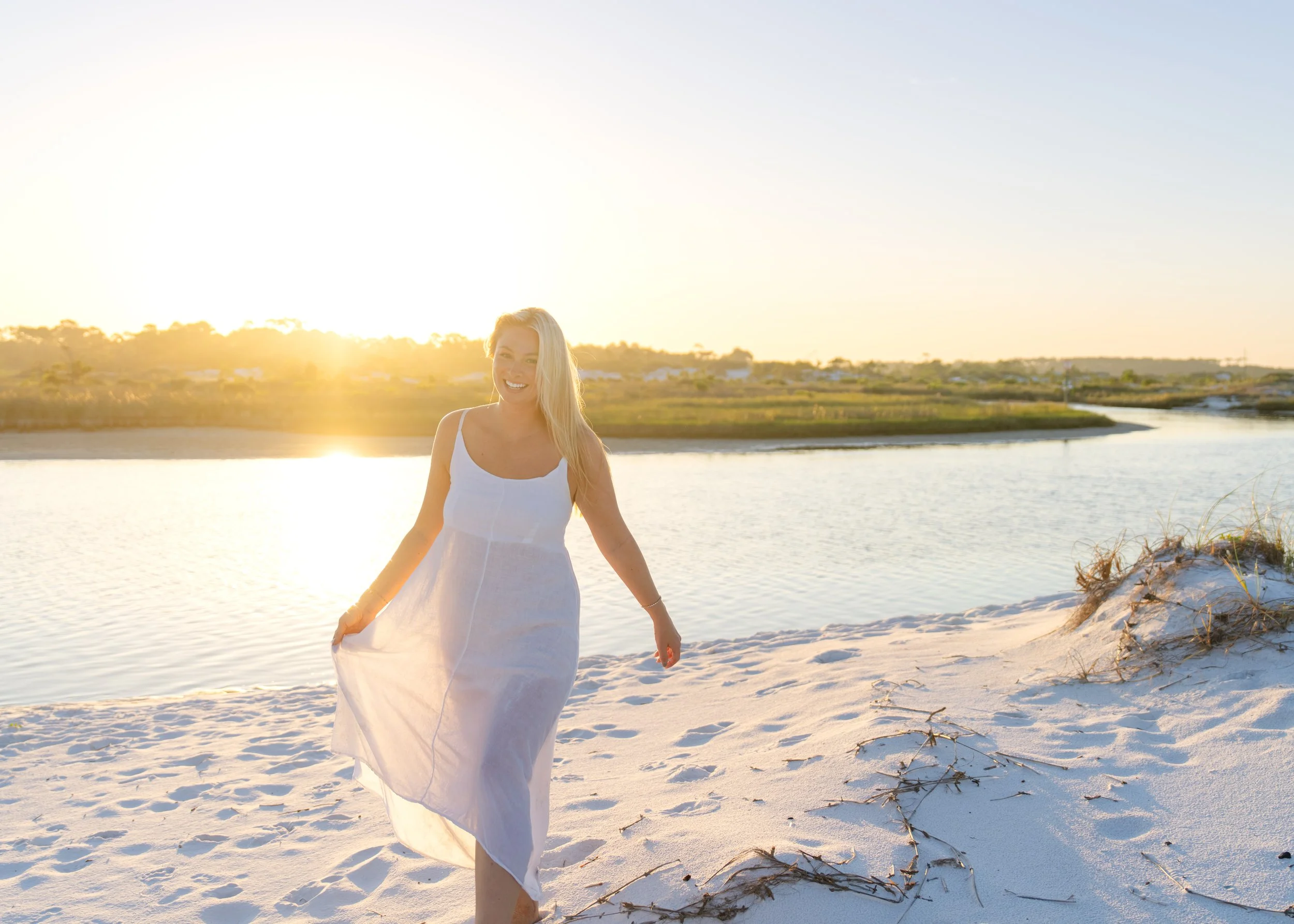 Portrait of a woman walking through the dunes with the sunrise behind her. Grayton Beach Photographer. 30A Photographer
