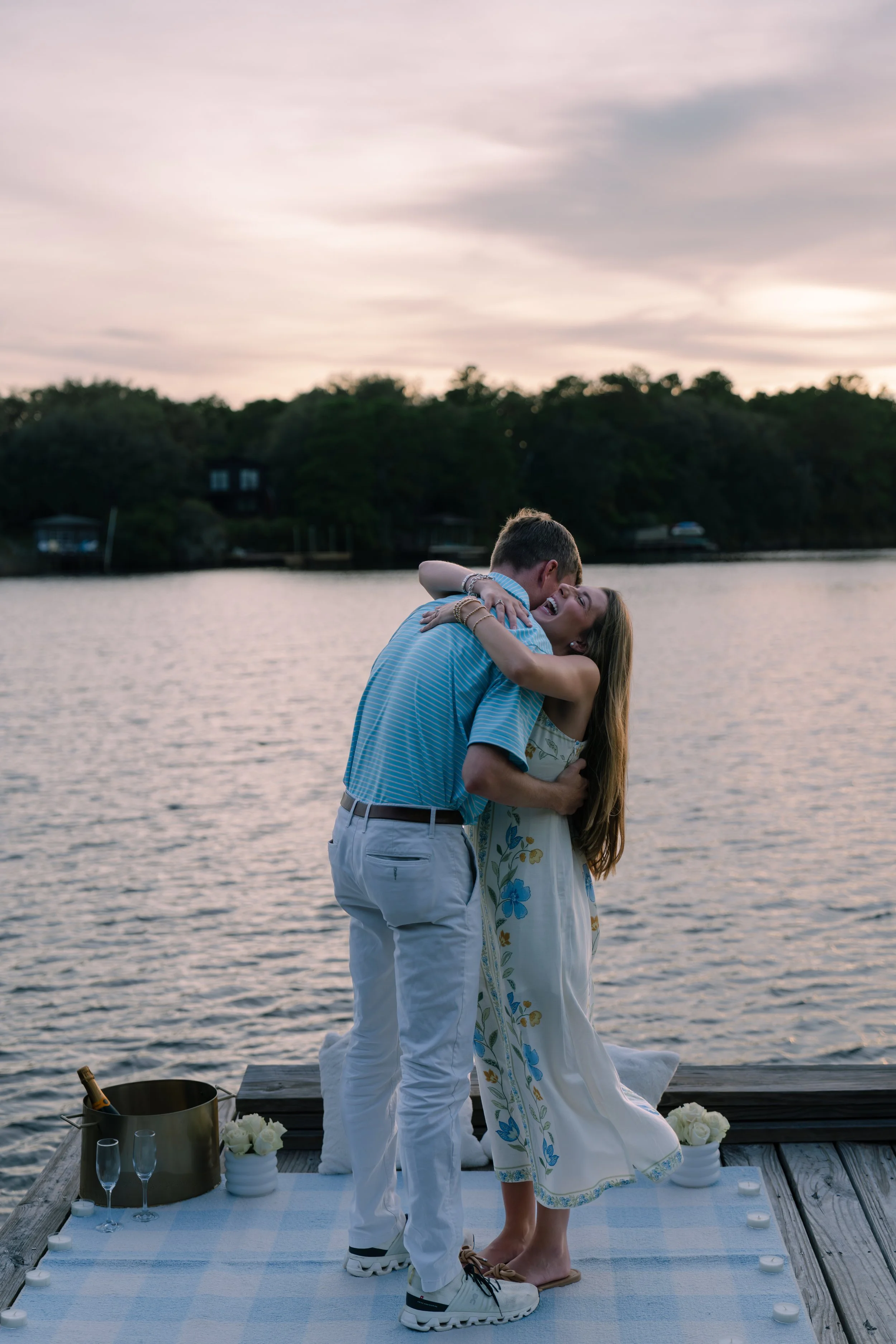 Man and woman hugging on a dock in the sunset. 30A Photographer