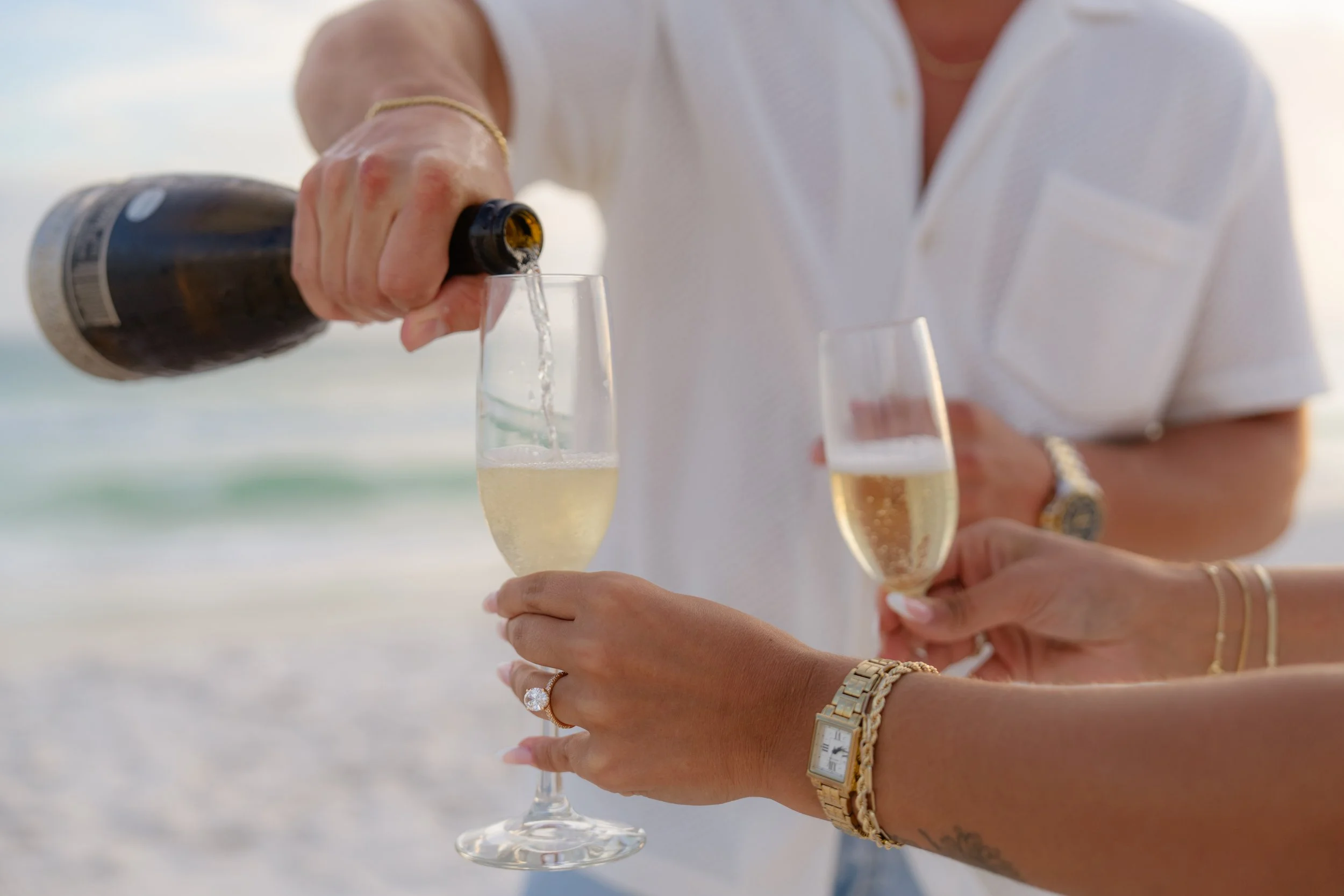 Man pouring a glass of champagne on the beach at sunset in 30A