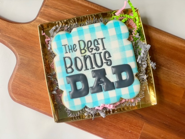 Decorated cookie in a gift box with the message "The Best Bonus Dad" written on it.