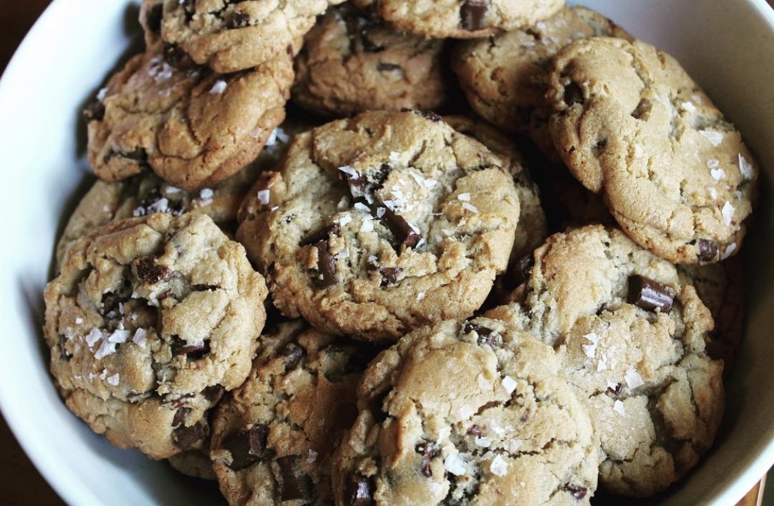A bowl filled with chocolate chip cookies topped with coarse sea salt.