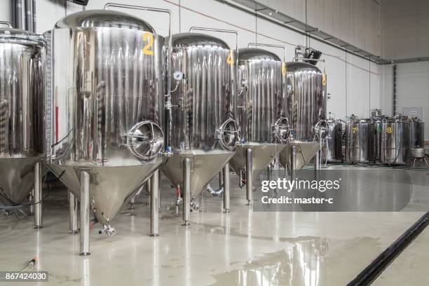 Rows of large stainless steel fermentation tanks in an avocado oil distillery equipment room.
