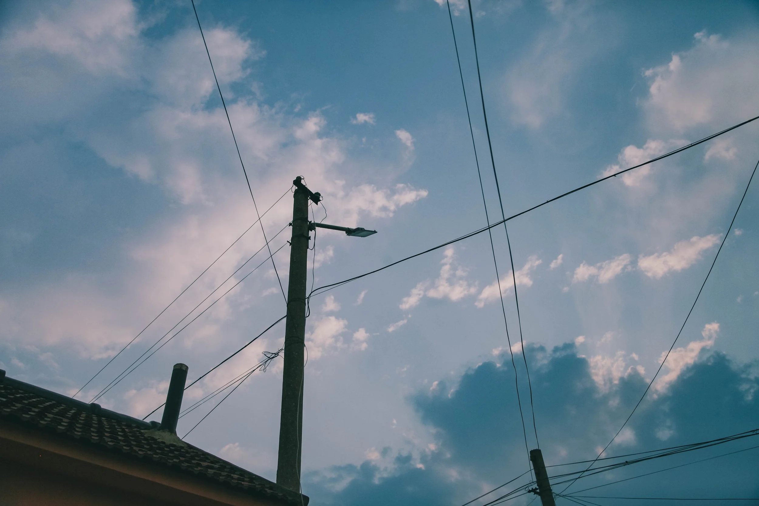 Utility pole with wires against a partly cloudy sky during daytime.
