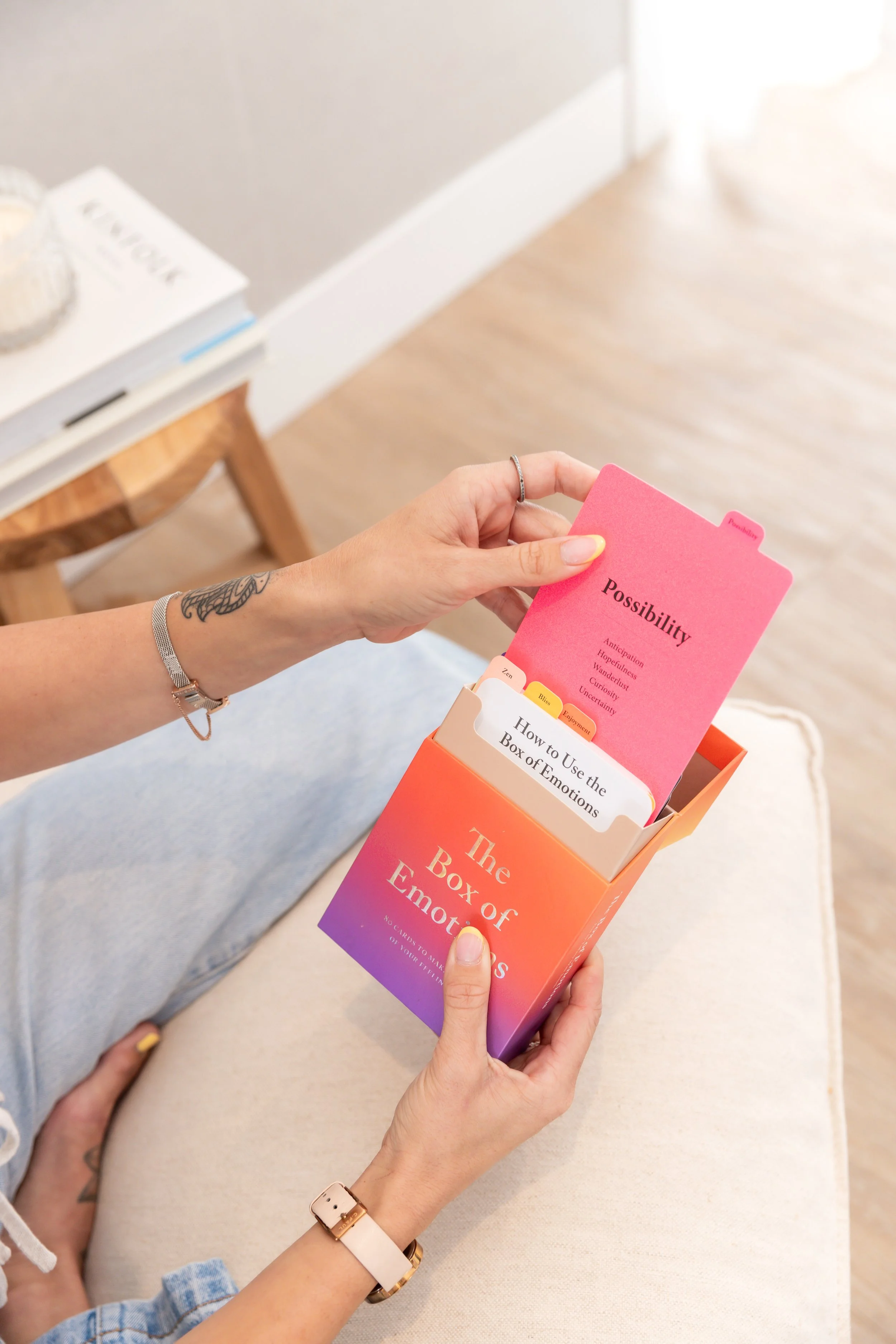 Person holding a colorful box labeled 'The Box of Emotions' and removing a pink card titled 'Possibility' from inside.