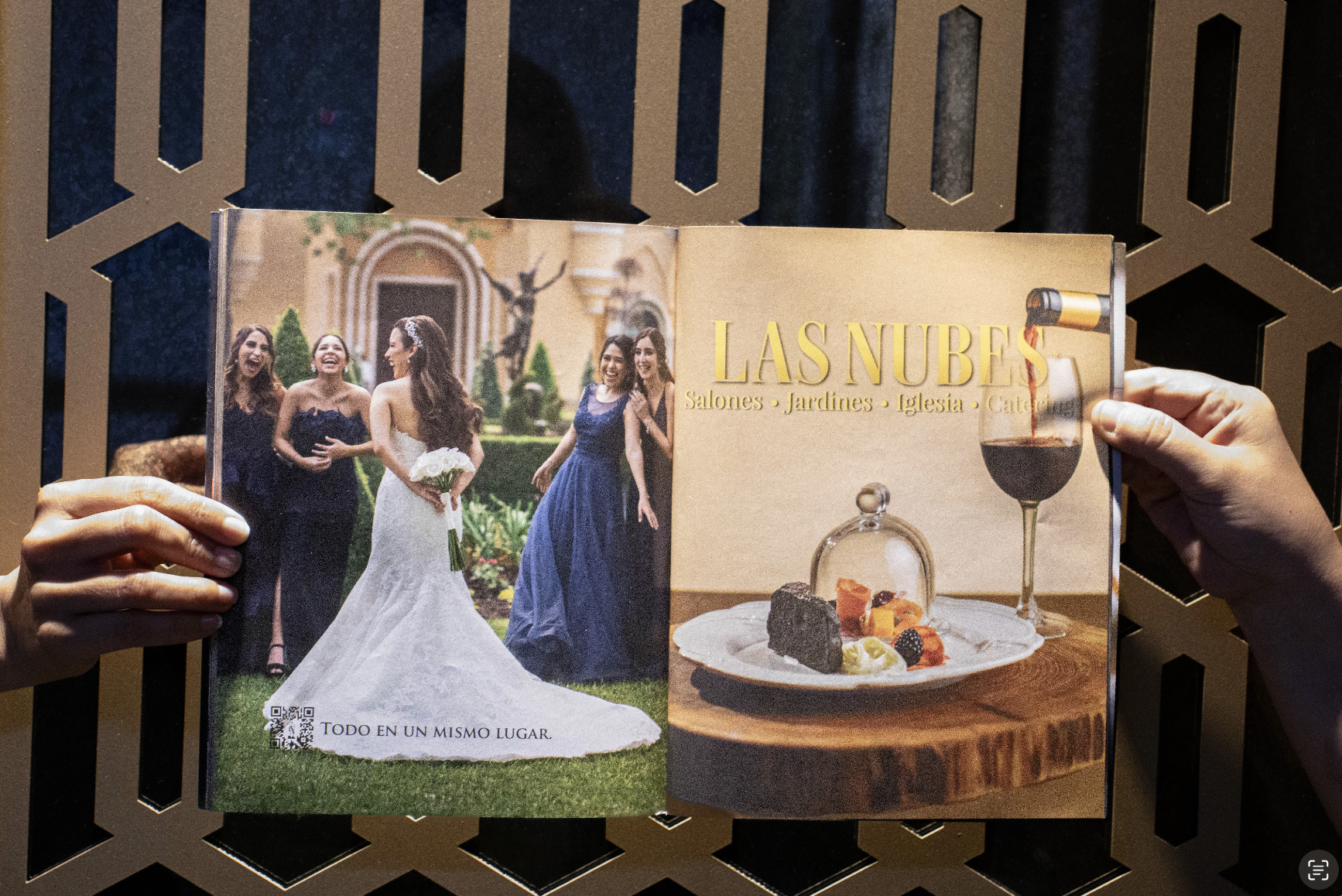Imagen de un folleto o catálogo con una página que muestra a un grupo de mujeres en un jardín y a la novia en un vestido de novia. La otra página tiene el título "LAS NUBES" y muestra un postre y una copa de vino tinto.