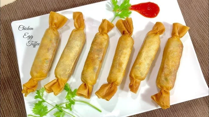 Six chicken egg tartlets wrapped in golden pastry, garnished with cilantro, served on a white plate with a side of ketchup and a sprig of cilantro.