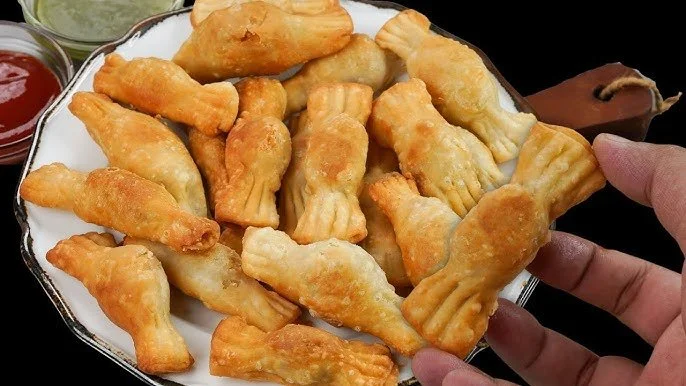 Fried chicken nuggets on a white plate with sauces in small cups nearby.