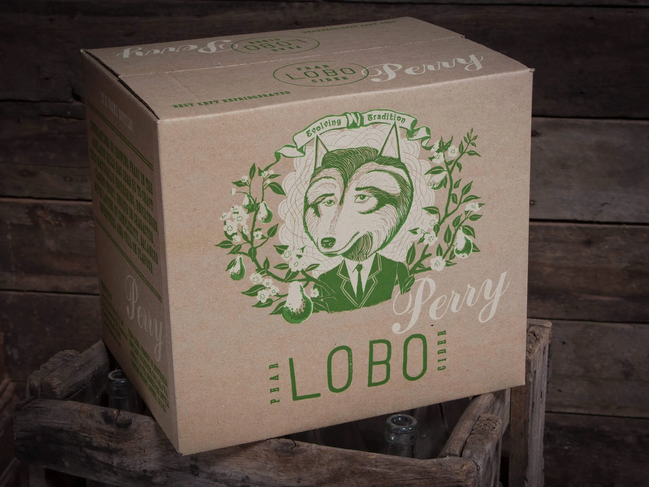 A cardboard box with green and white printing featuring an illustration of a dog in a suit surrounded by floral elements, placed on a wooden surface with a rustic wood background.