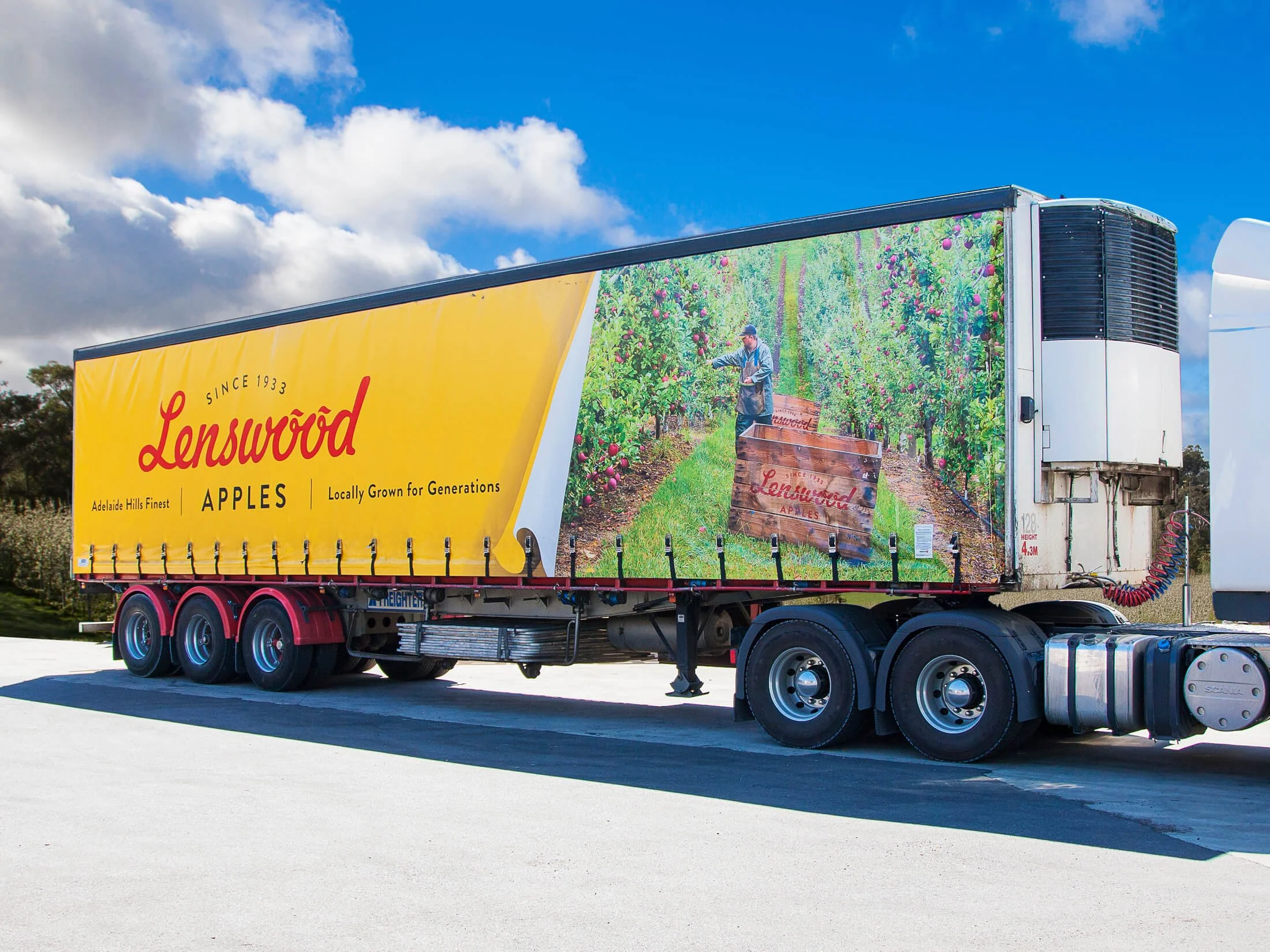 Lenswood Apples advertisement on a truck with a scenic apple orchard image and a worker picking apples.