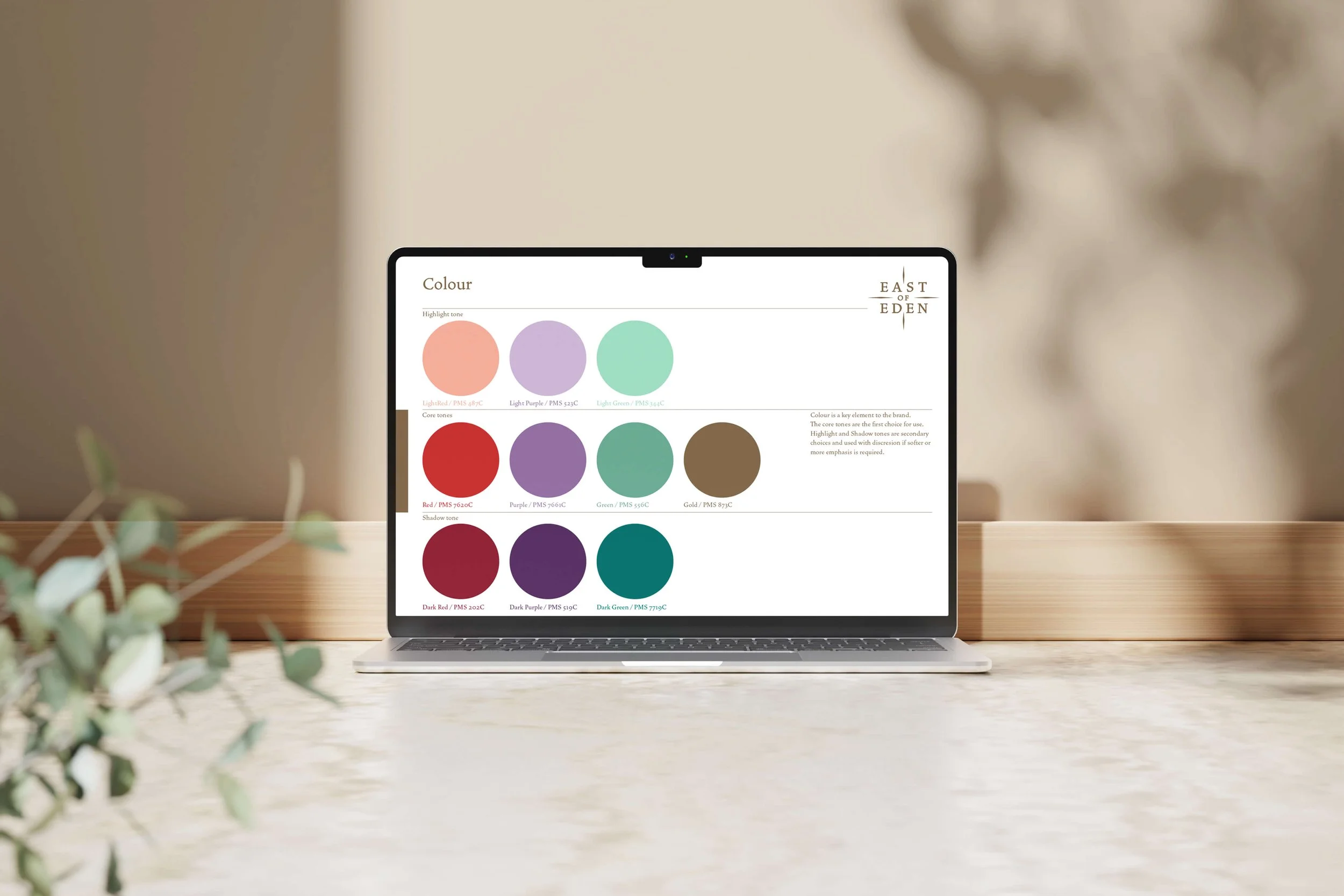 Laptop displaying a color palette chart with various shades of purple, green, red, brown, and teal, and a small text box with branding from East of Eden.