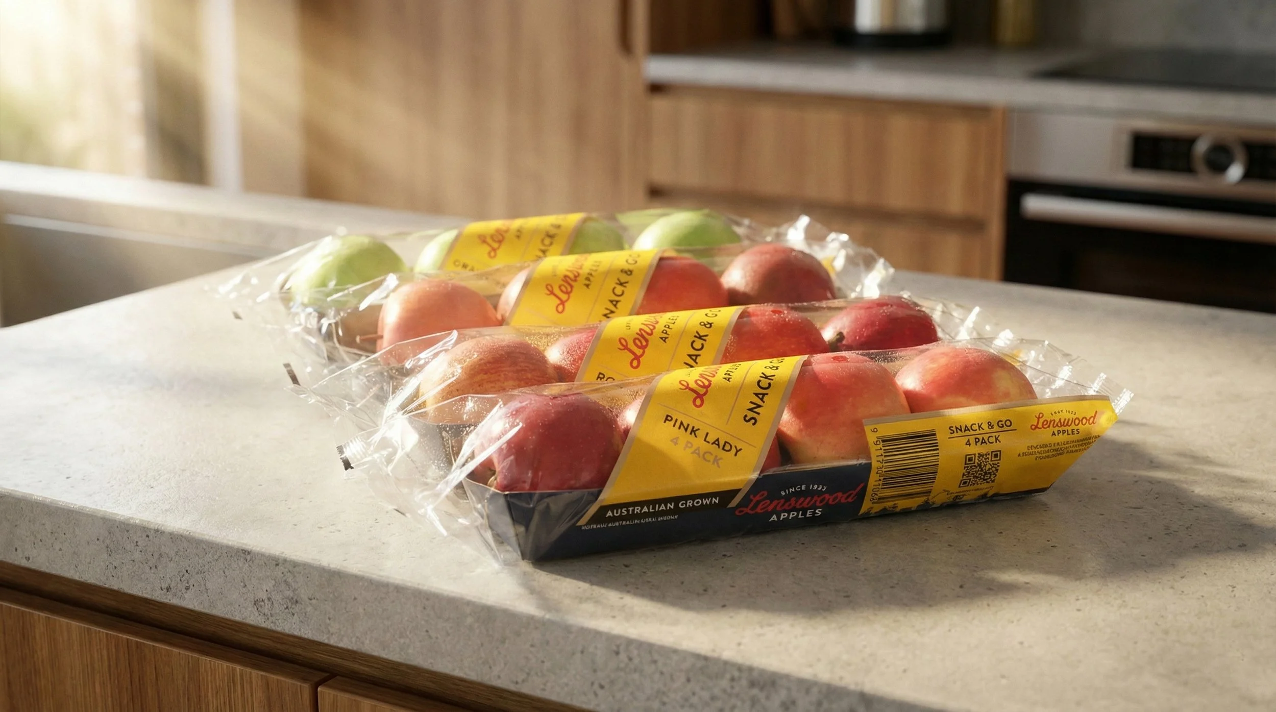 Three packs of Lenswood apples on a kitchen countertop, one with green apples and two with red apples.