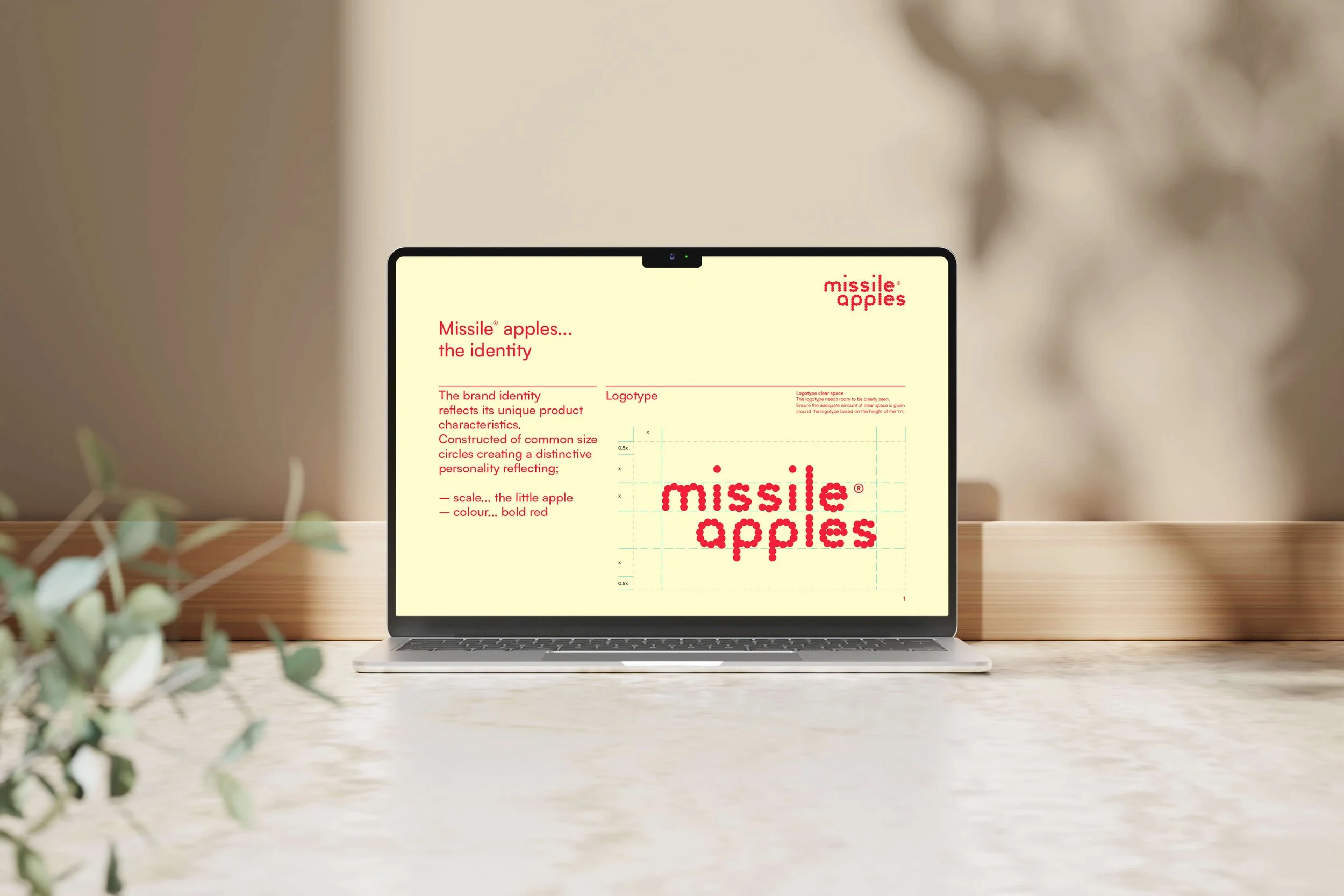 A laptop on a wooden desk displaying a presentation about Missile Apples, featuring their brand identity and logo in a pixelated red font.