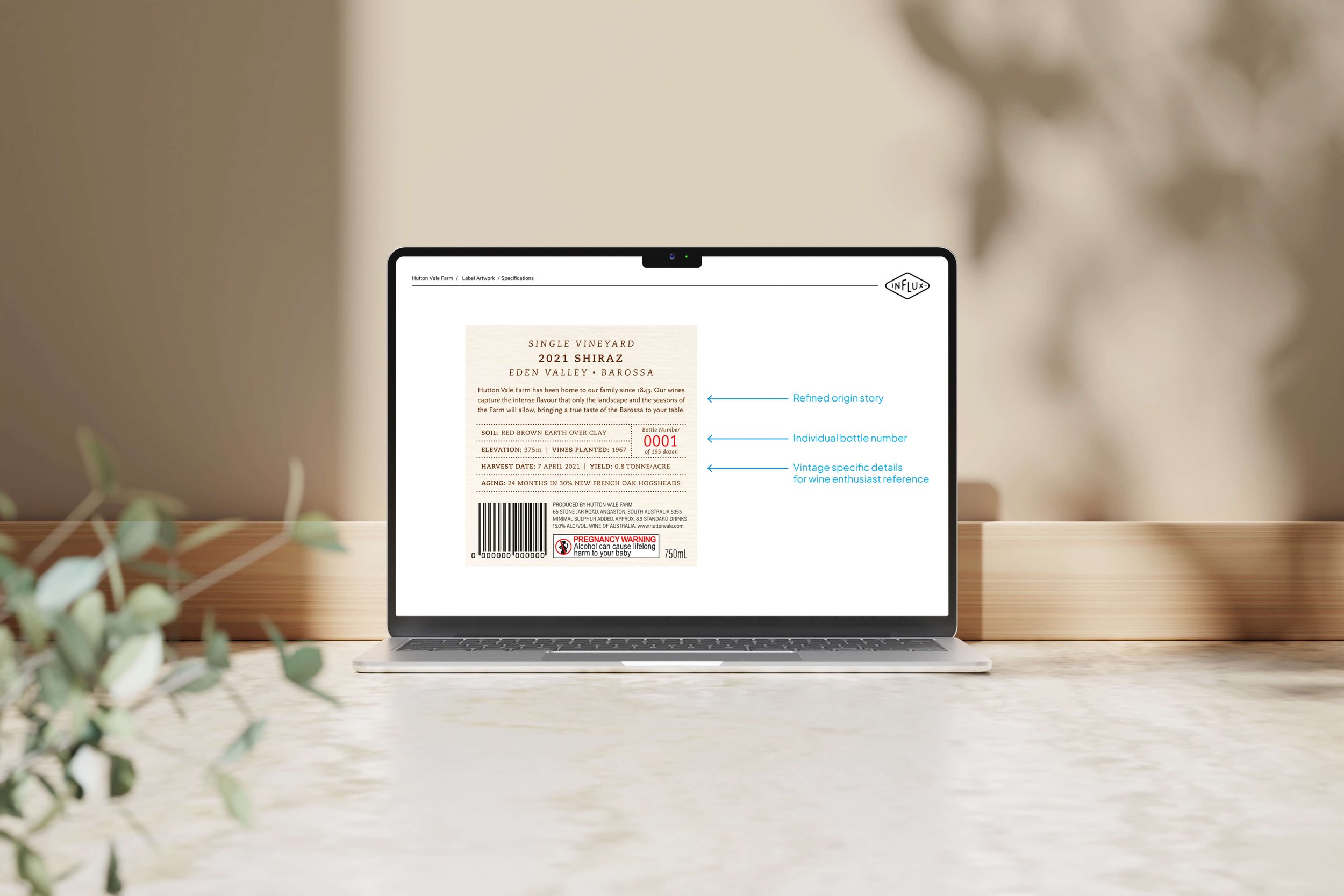 Laptop displaying a wine label with detailed information and annotations for origin story, bottle number, and specific wine details.