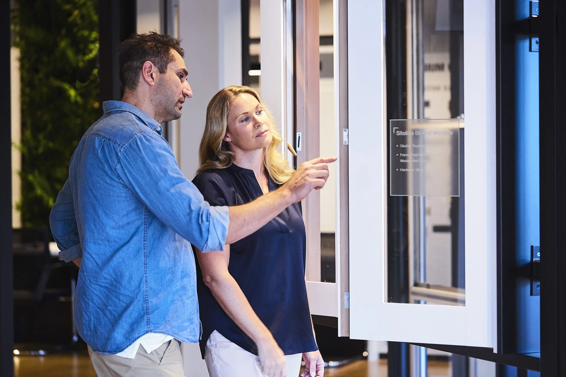 A man and woman looking at a display at an indoor exhibition or showroom.