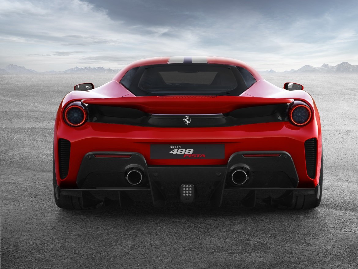 Rear view of a red Ferrari 488 Pista with dual exhausts and aerodynamic diffuser, set against an open landscape background.