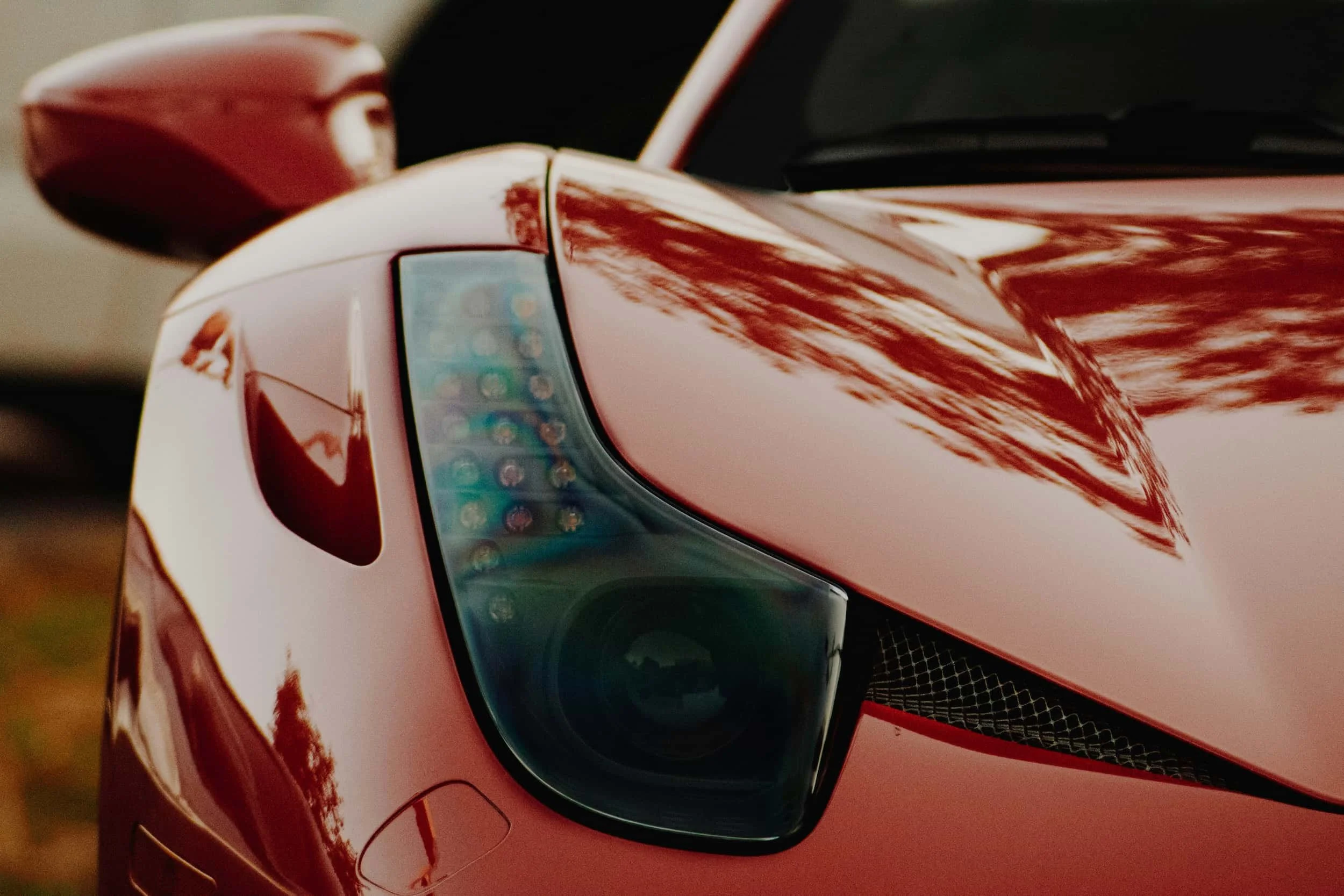 Close-up of a Ferrari headlight, symbolising luxury performance vehicles available through tailored finance solutions.