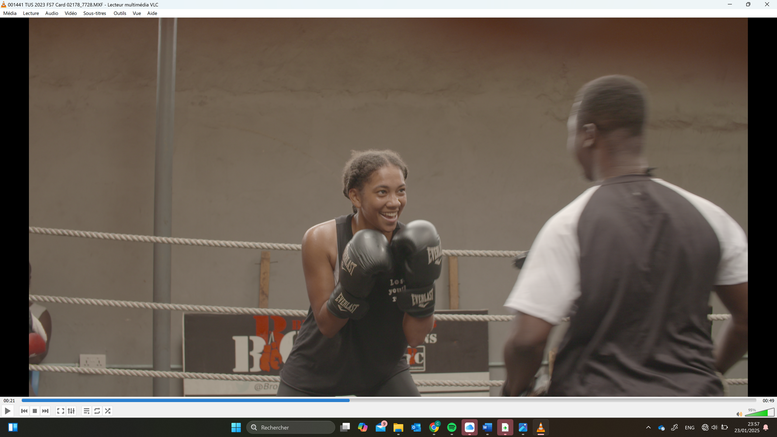 A woman in boxing gloves sparring with a trainer in a boxing gym, both smiling and engaging during training.