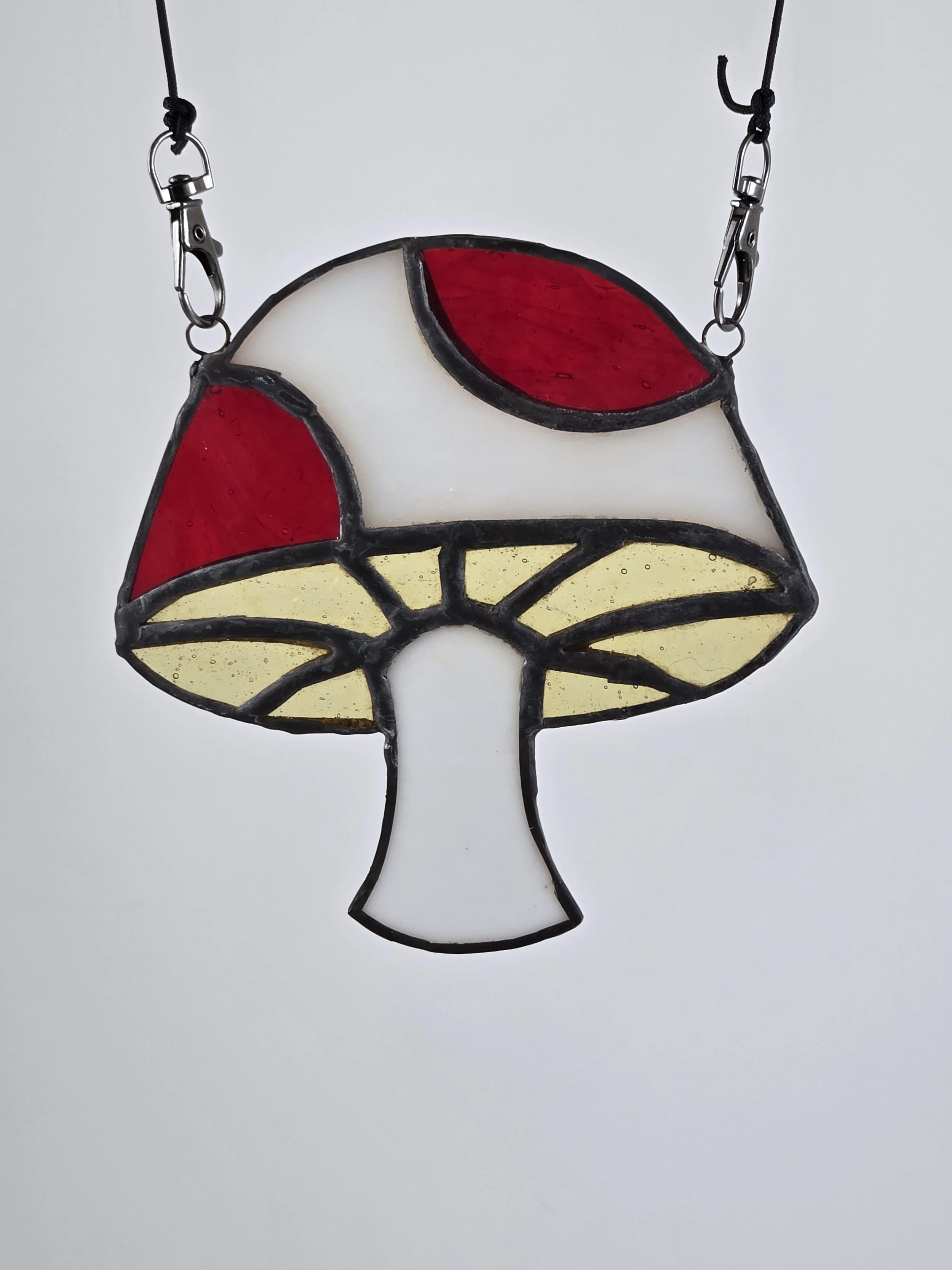 Colorful stained glass mushroom suncatcher with red, white, and yellow glass panels.