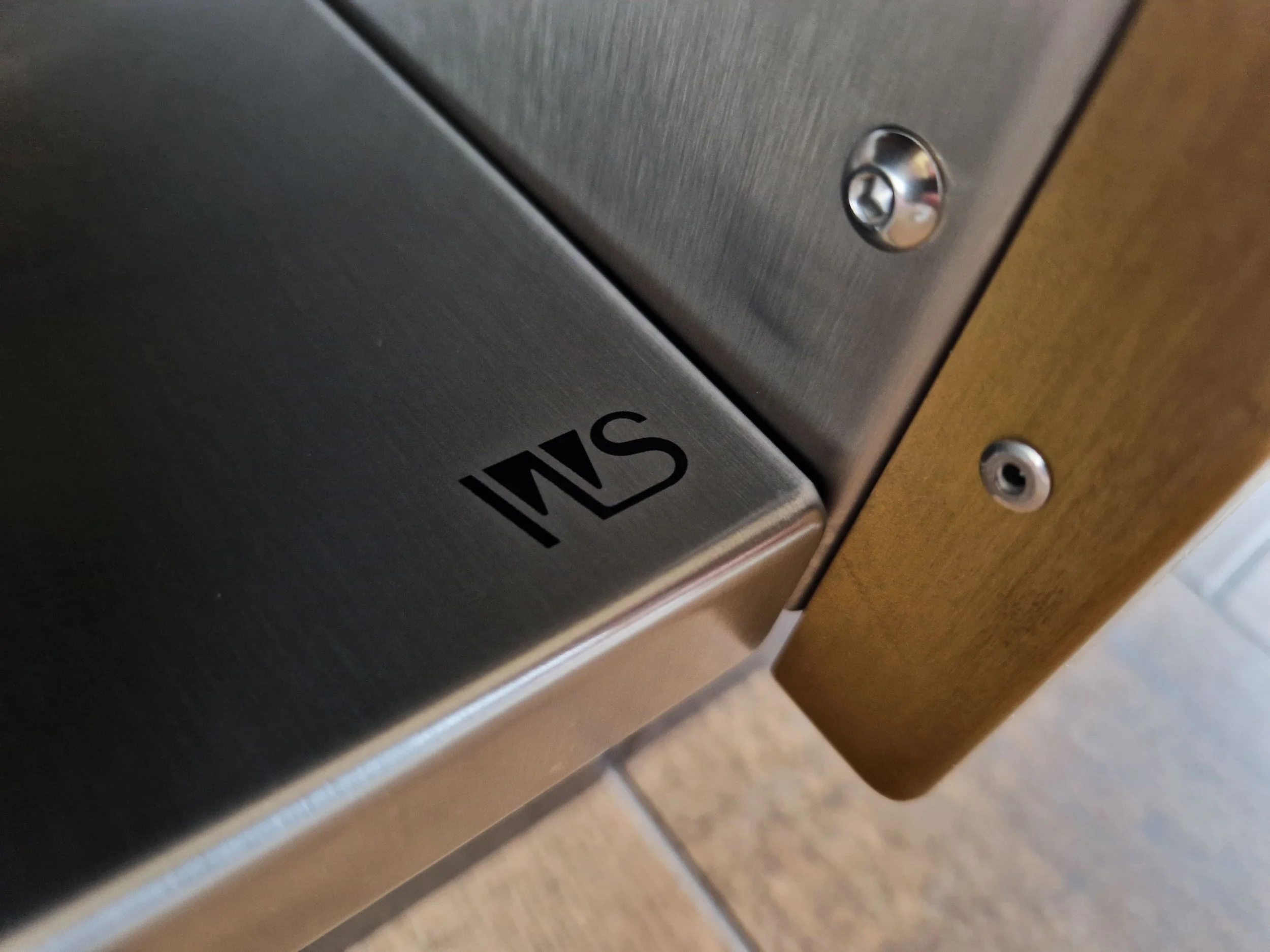 Precision-machined stainless steel component featuring laser-etched WodenStel branding and meticulously finished metalwork details.