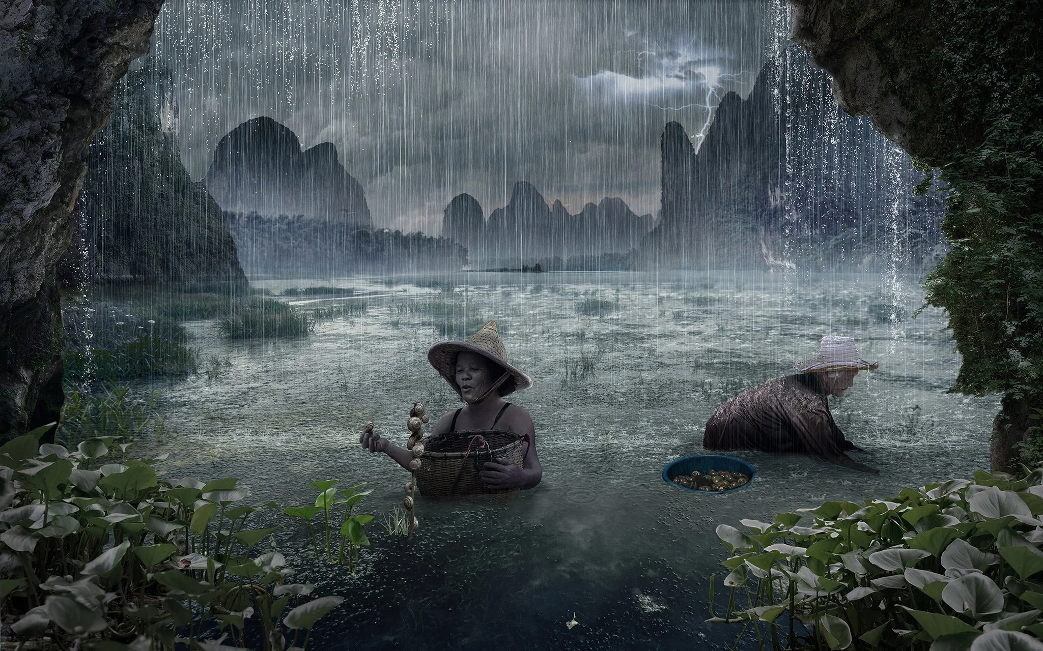Two women wearing conical hats wade in a flooded landscape during a storm, with mountains and rain in the background.