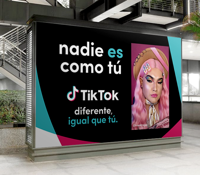 A billboard with a black background displays social media promotional content in Spanish. It features the TikTok logo and a photo of a woman with pink hair, wearing a straw hat, colorful hair clips, and makeup. The text says, "nadie es como tú" and "diferente, igual que tú," which translates to "no one is like you" and "different, just like you." The design includes teal, pink, and white accents.