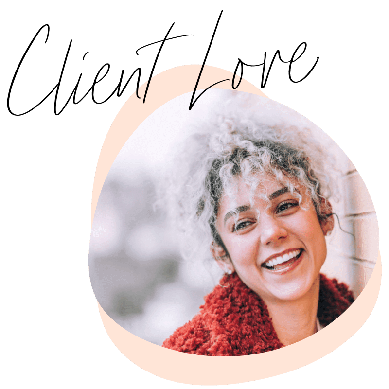 A smiling woman with curly hair and a striped shirt, wearing a red fuzzy jacket, standing outdoors near a wall.