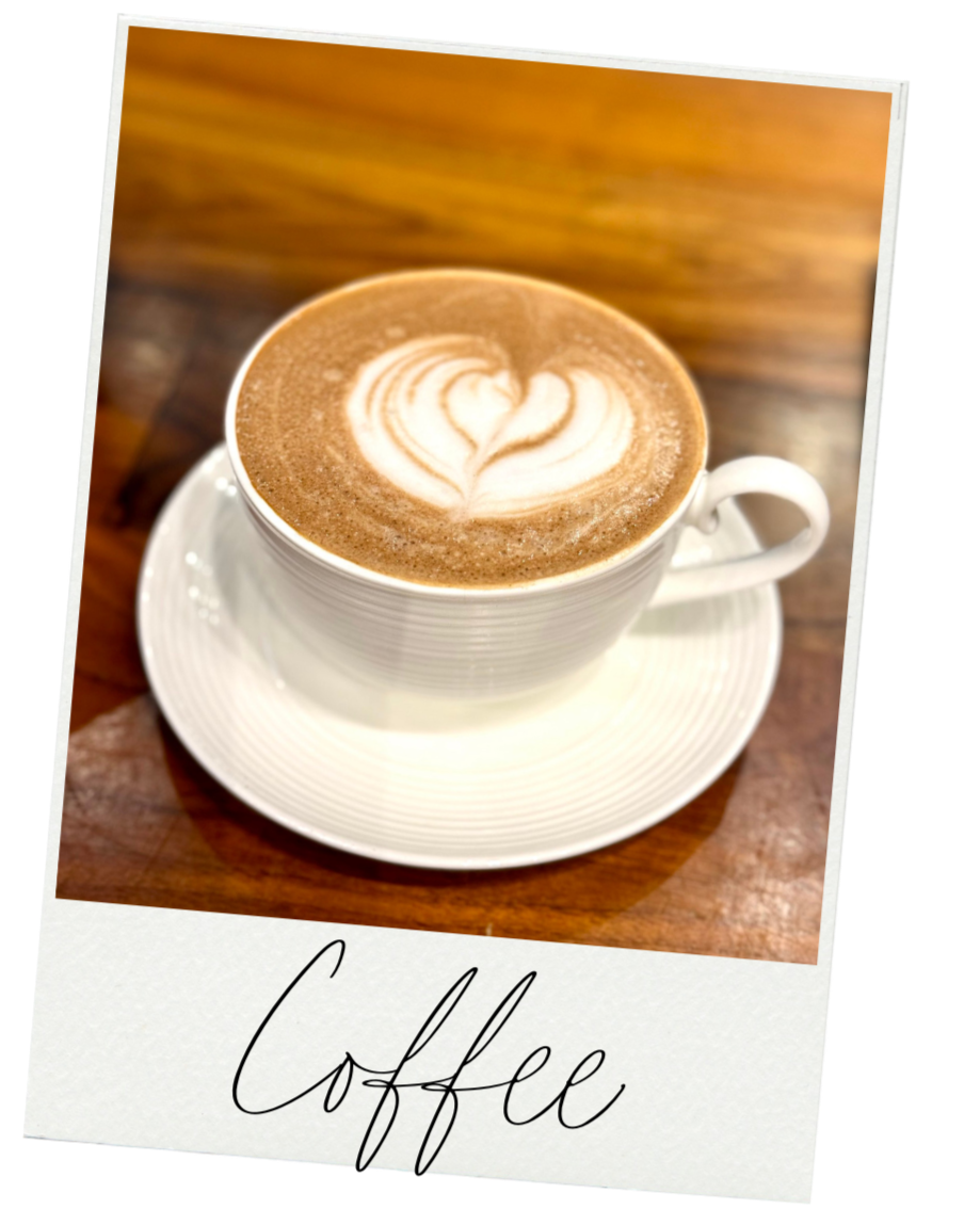 A cup of coffee with latte art in the shape of a heart, served in a white cup on a matching saucer on a wooden table. The word 'Coffee' is written in cursive at the bottom of the image.