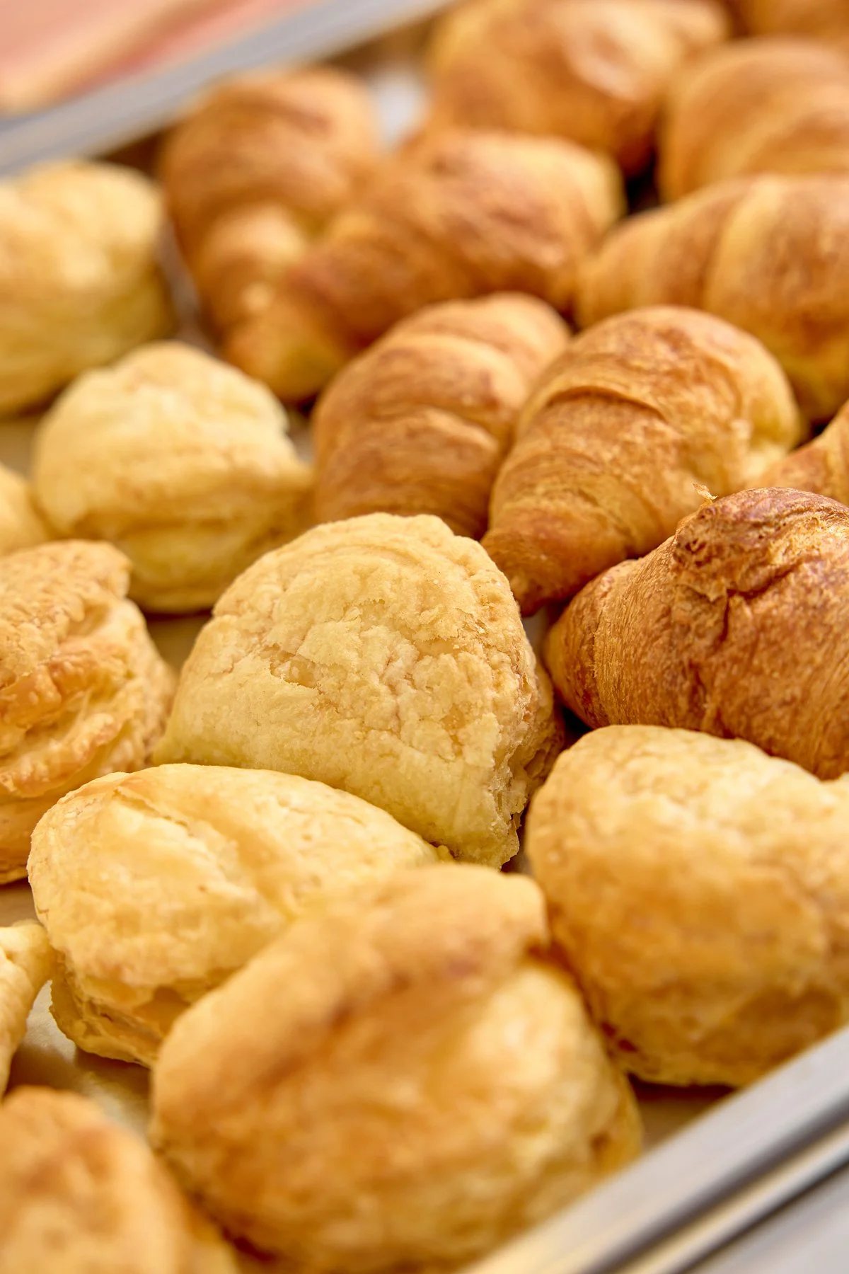 Assorted baked goods including croissants and cream puffs on a tray.