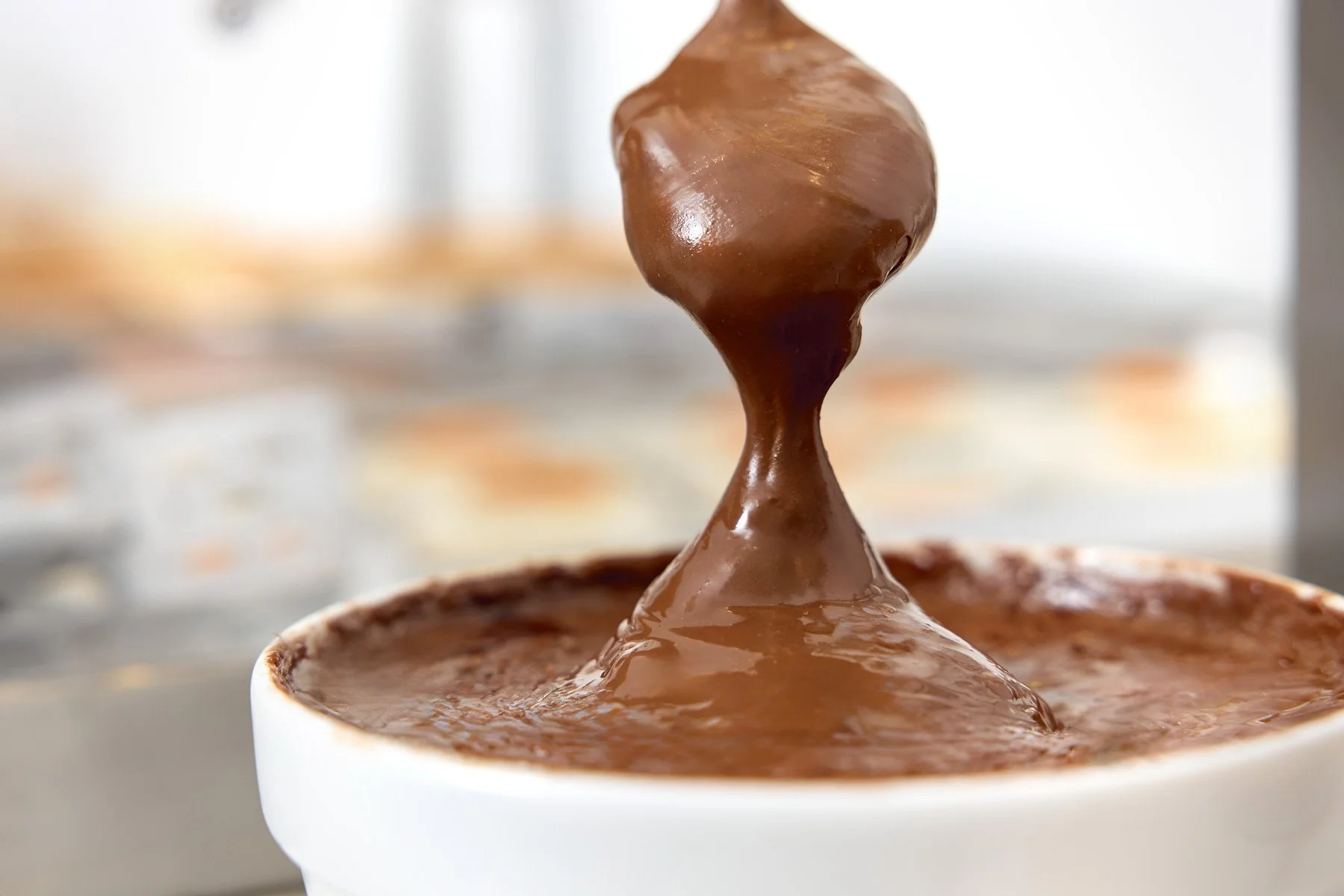 Close-up of melted chocolate being poured into a white bowl.