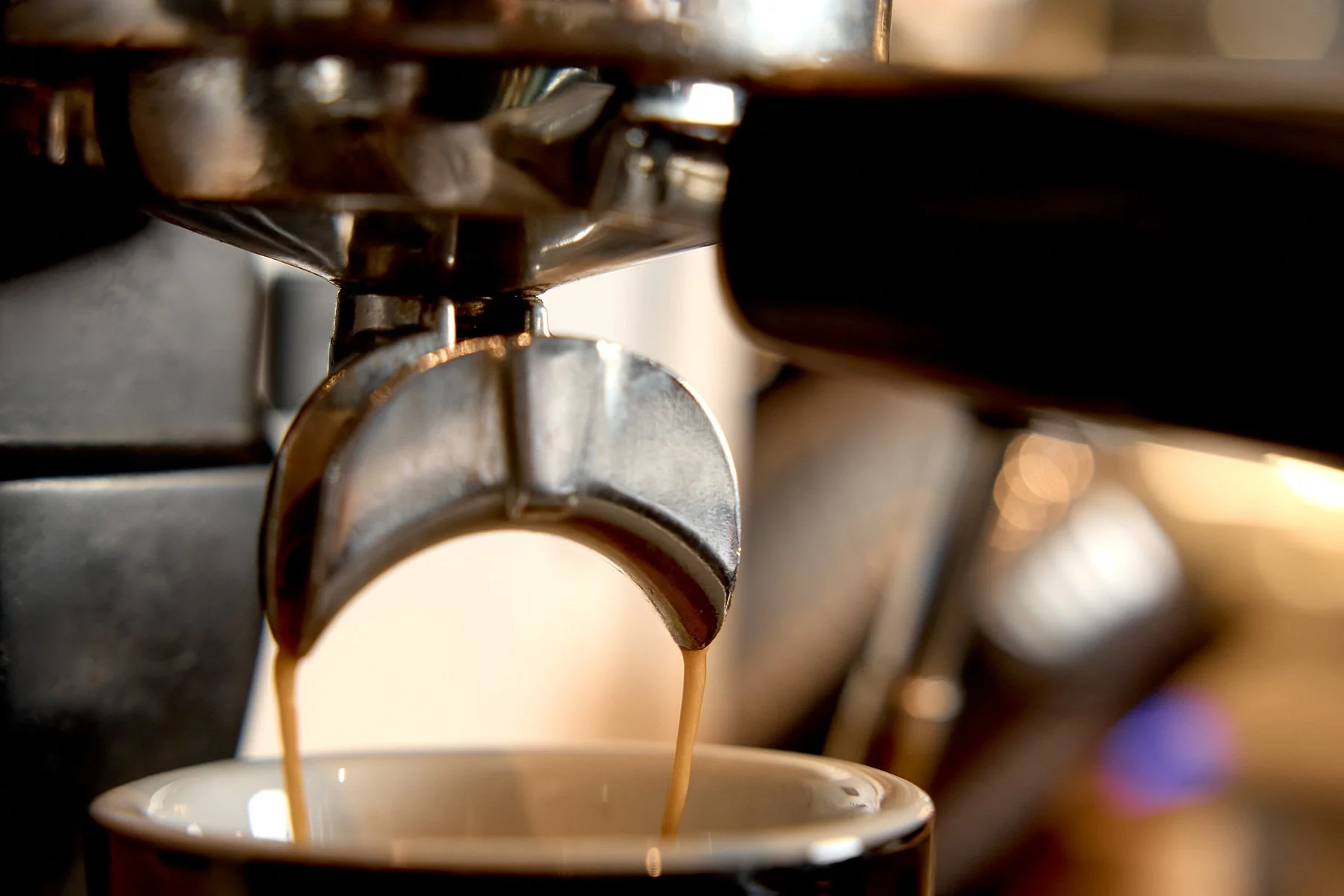 Close-up of a coffee espresso machine pouring espresso into a white cup.