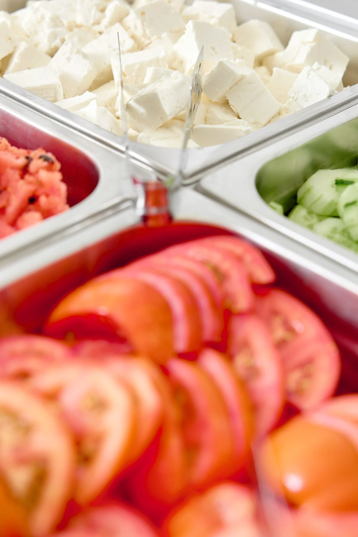 Fresh cut vegetables and cheese in a salad bar station.