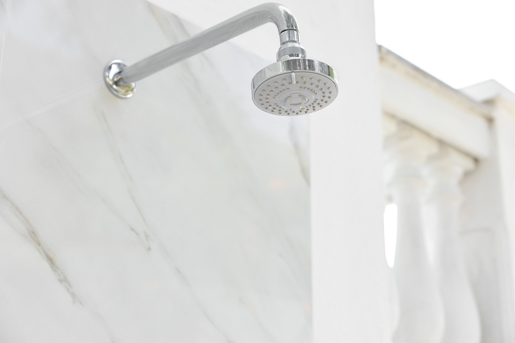 Showerhead mounted on a white tiled bathroom wall