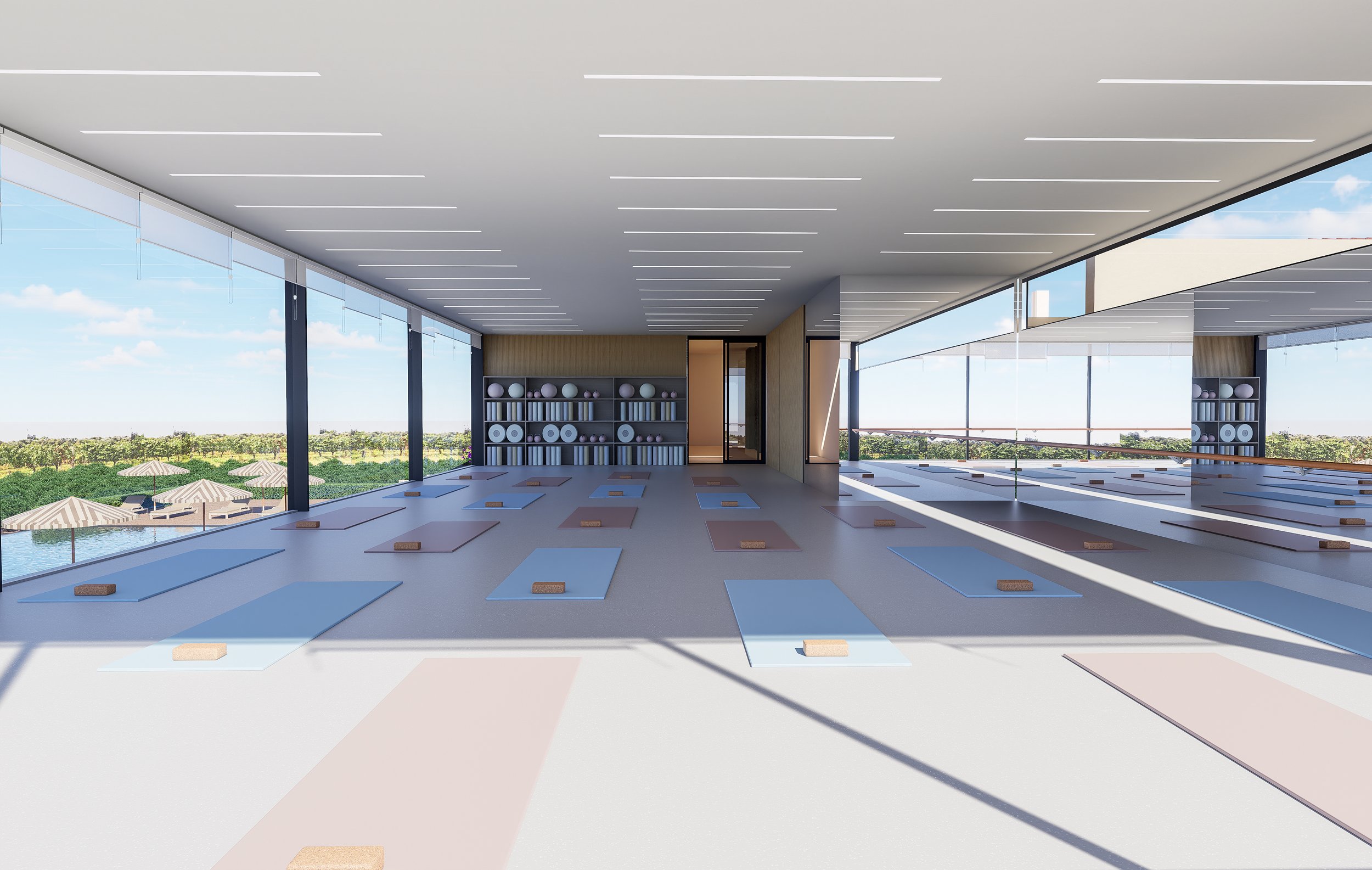 A modern yoga studio with large floor-to-ceiling windows, yoga mats and blocks arranged on the floor, and shelves with yoga props at the back, overlooking a scenic outdoor view with umbrellas and greenery.