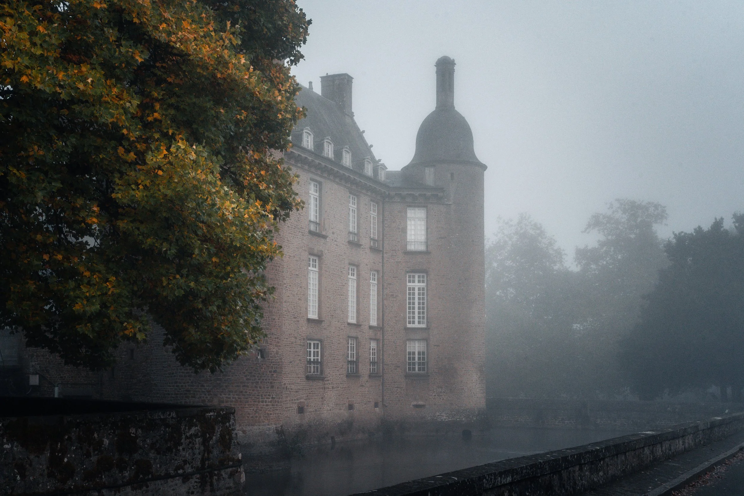 Château de Flers, entouré d'arbres, dans une brume matinale.