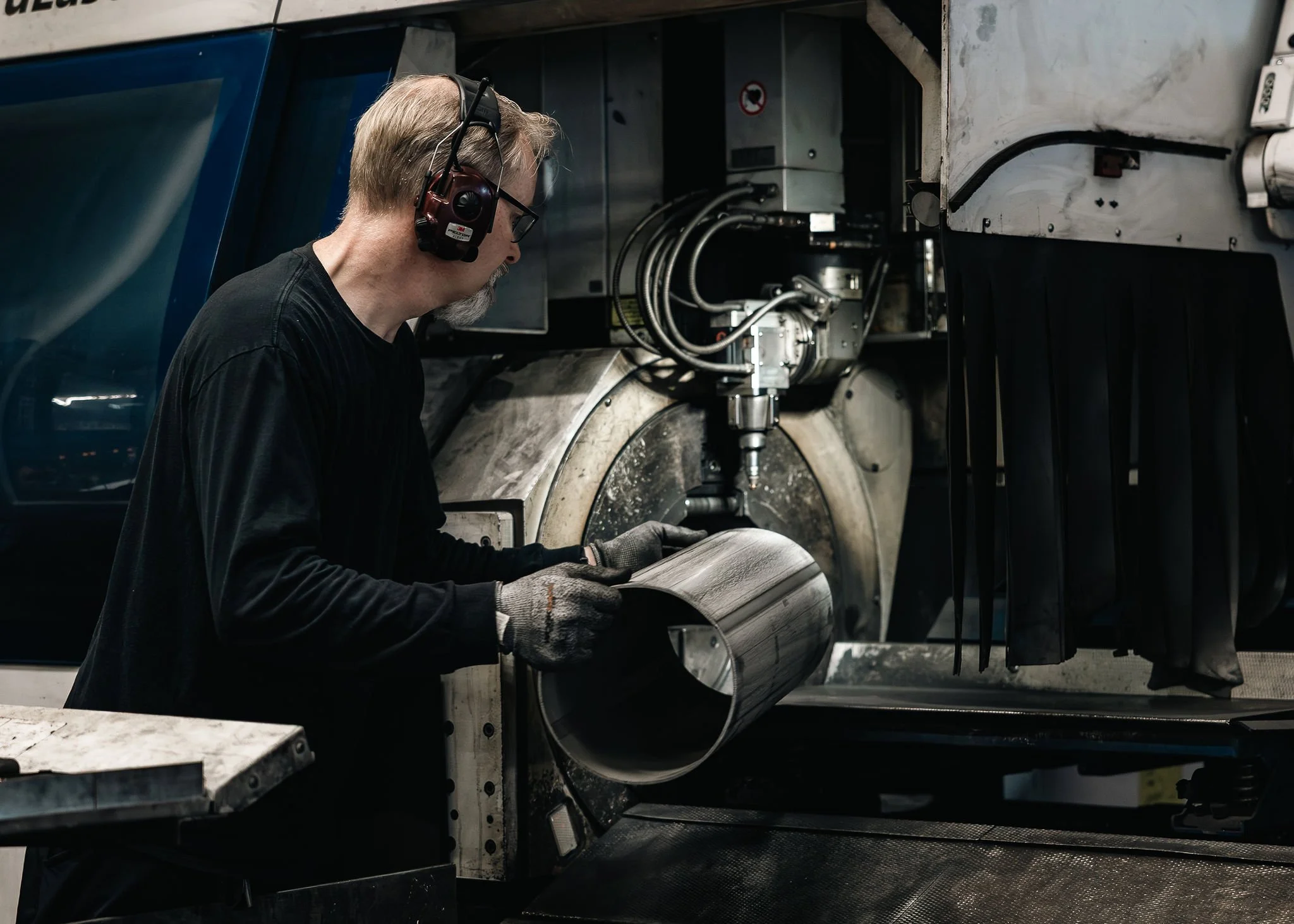 yöntekijä putkilaserkoneella käsittelemässä metalliputkea.