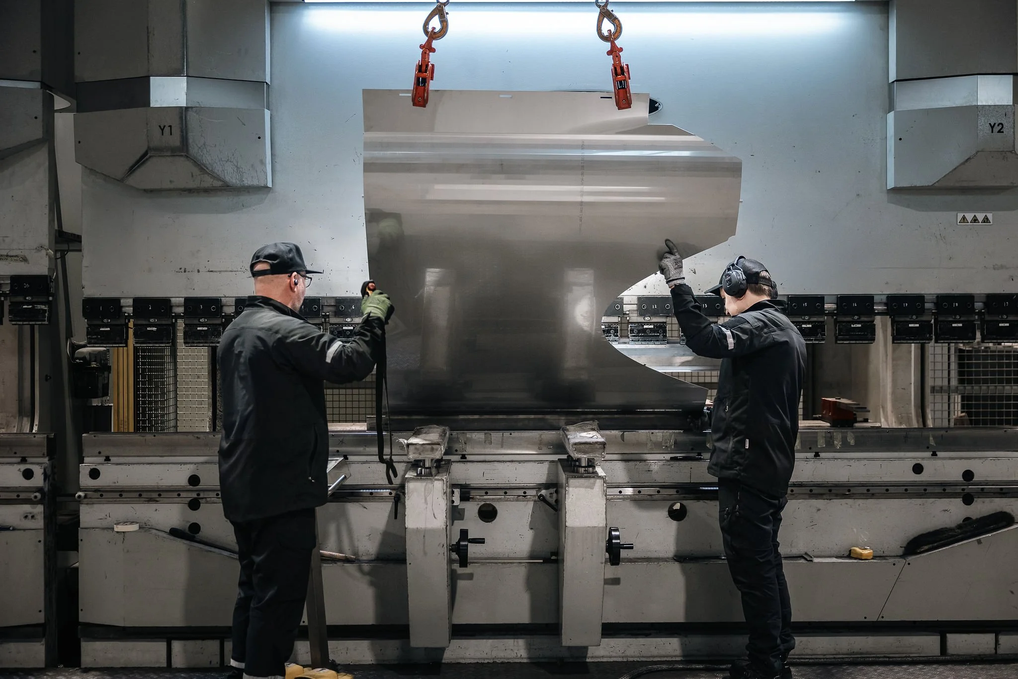 Kaksi työntekijää käyttämässä suurikokoista särmäyskonetta teollisuustilassa.