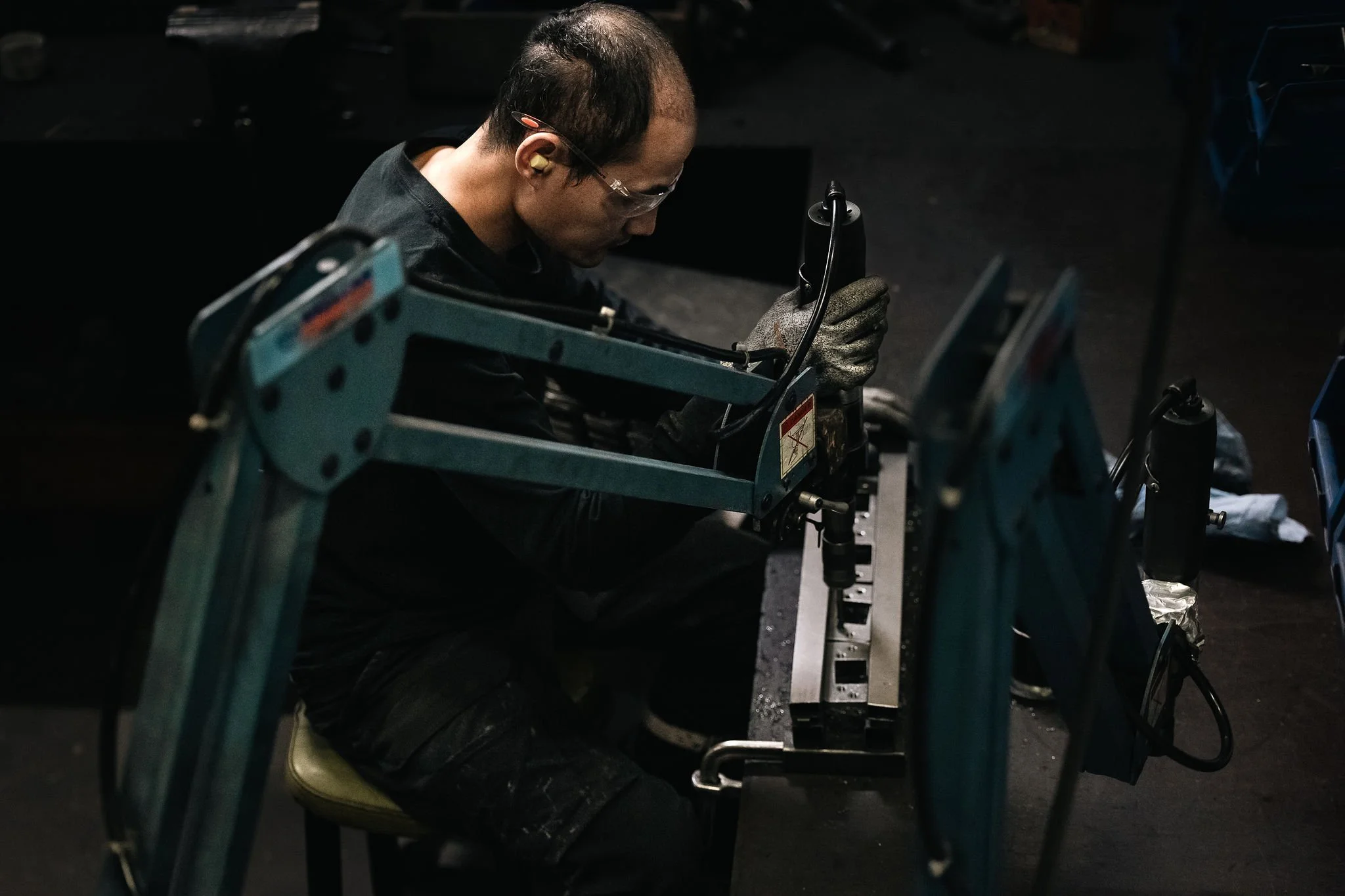 Työntekijä kierteyttämässä metalliosaa tarkassa työvaiheessa.