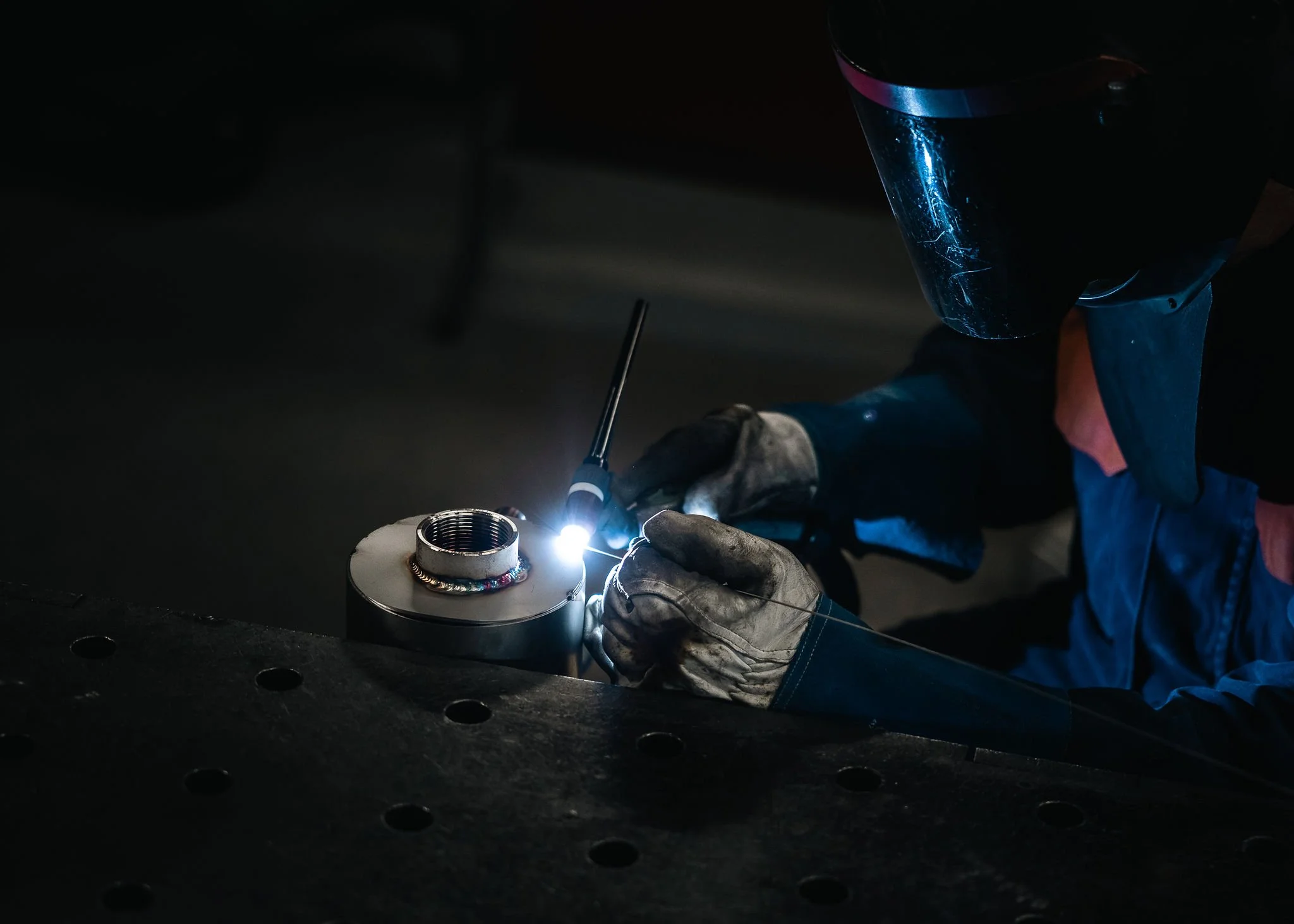 Hitsaaja työskentelemässä valokaaren kanssa metallikomponentin parissa.