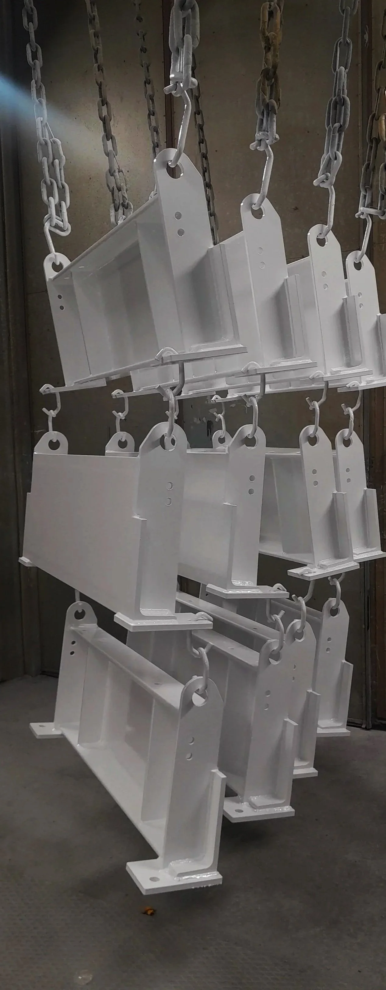 Metalliosia roikkumassa pintakäsittely- tai maalauslinjastolla.