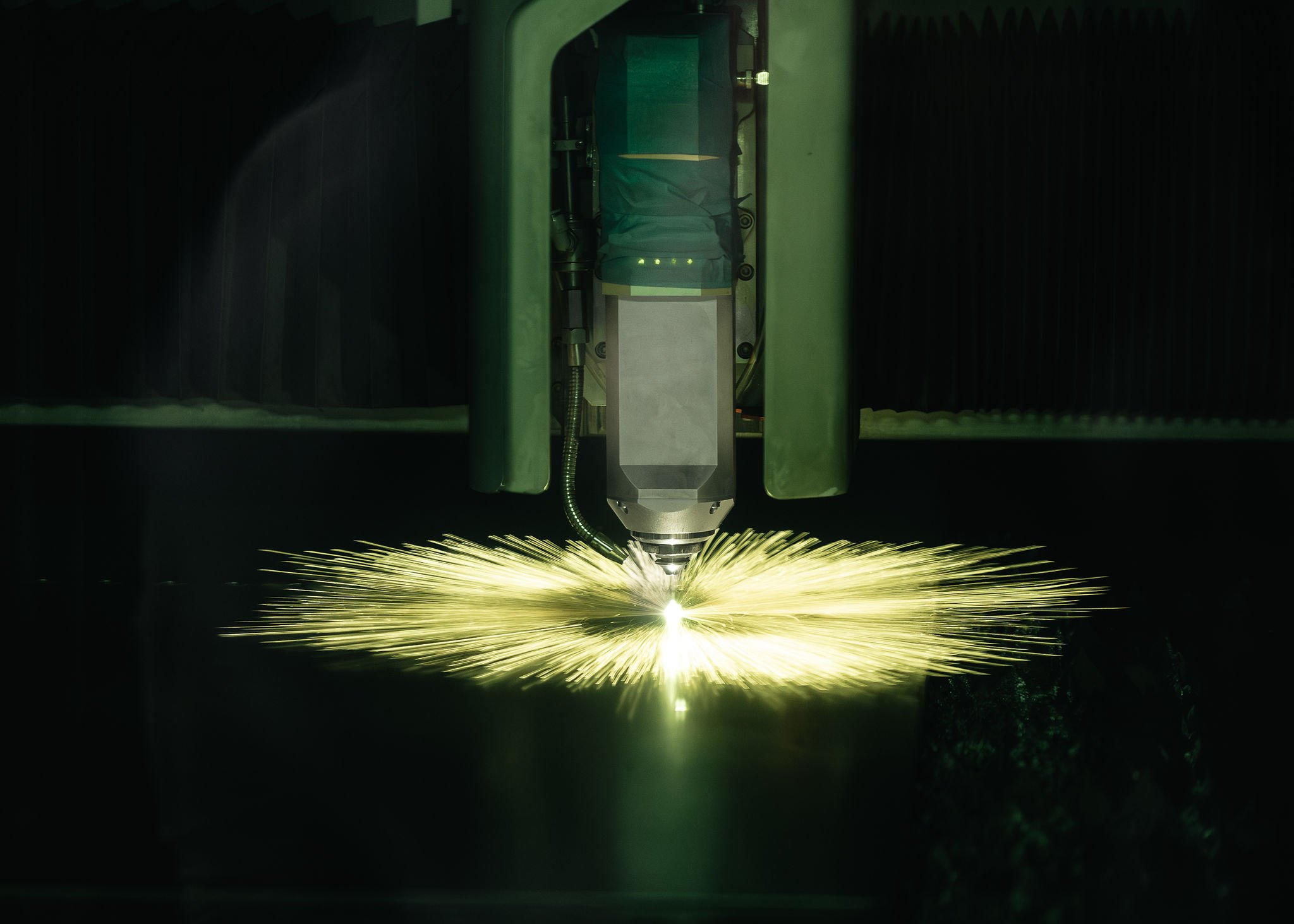 Tasolaserleikkauskone leikkaamassa teräslevyä kipinöiden.