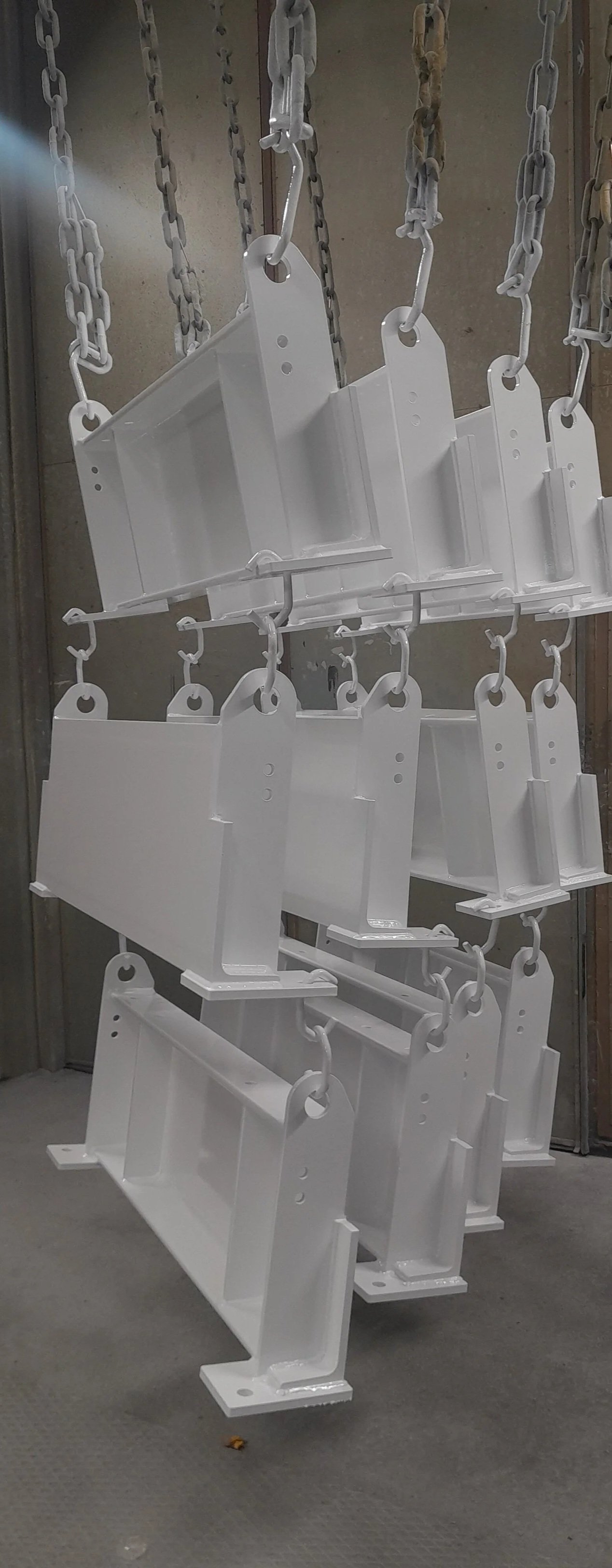 Ripustettuja pintakäsiteltyjä metalliosia pintakäsittelylinjalla.