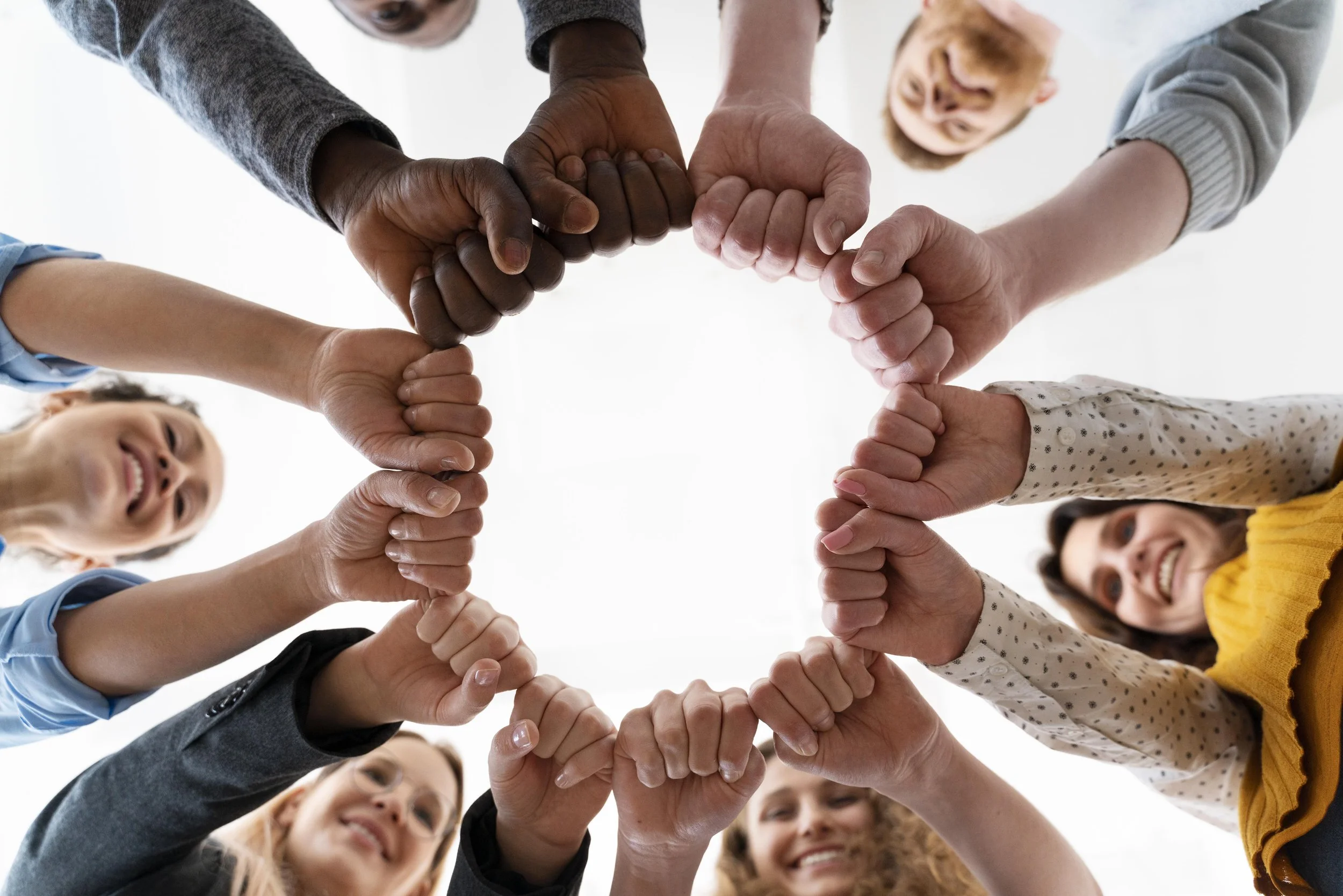 People forming a circle with their hands, holding each other's wrists to create a star shape, viewed from below.