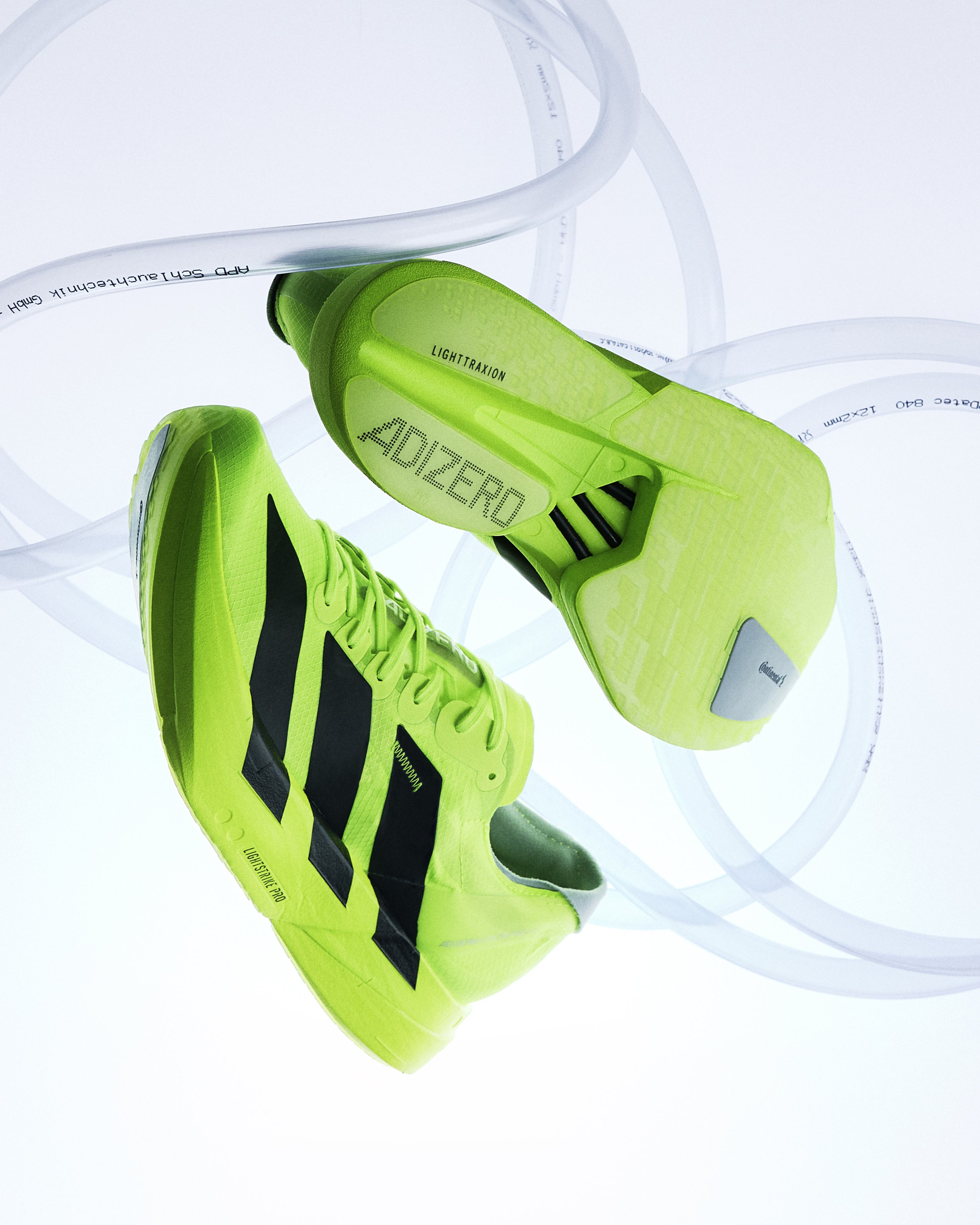 Bright green Adidas football shoes with black stripes, displayed upside down with white ribbon-like material around.