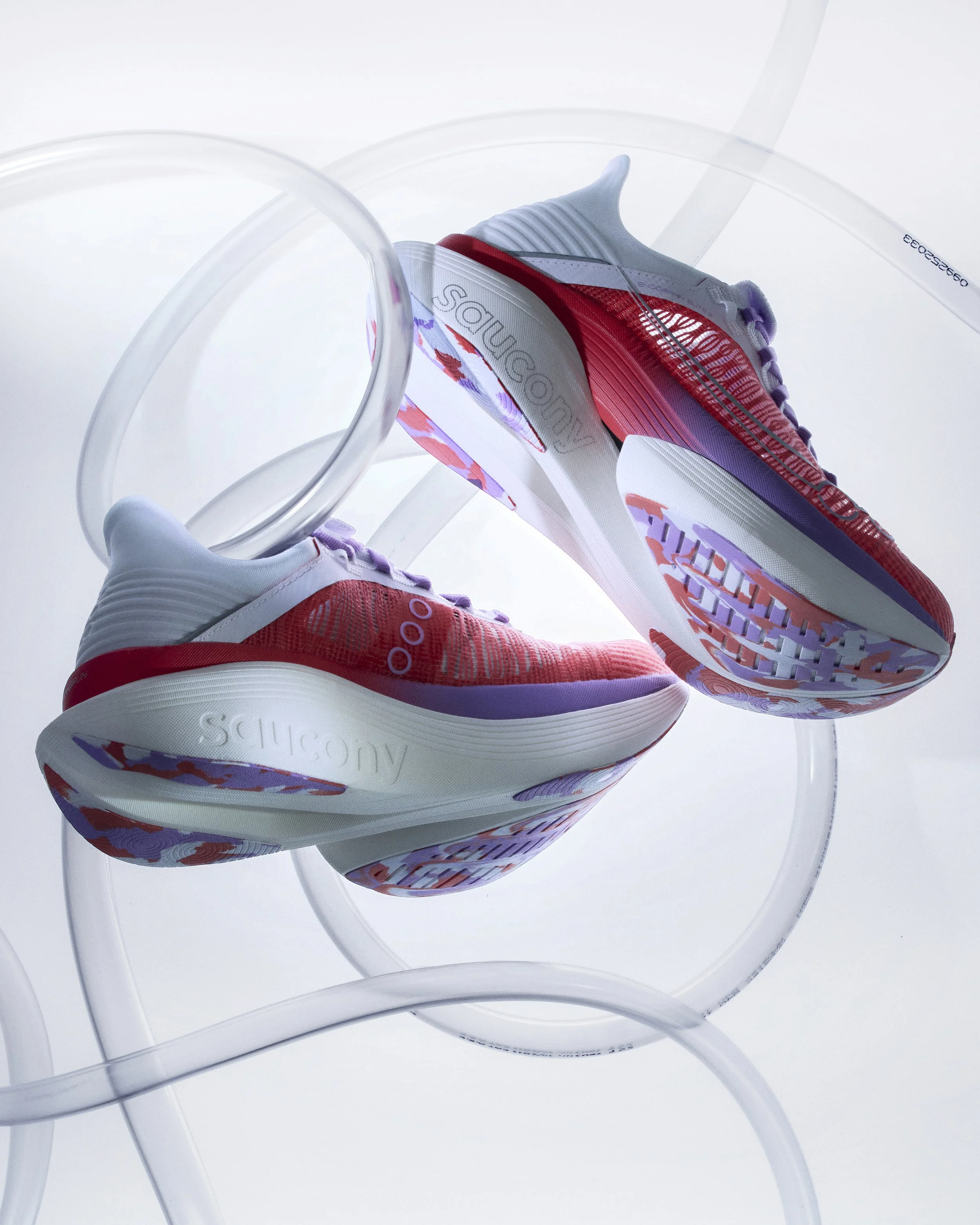 A pair of colorful athletic sneakers with a white sole and purple accents, displayed on a clear acrylic stand against a plain white background.