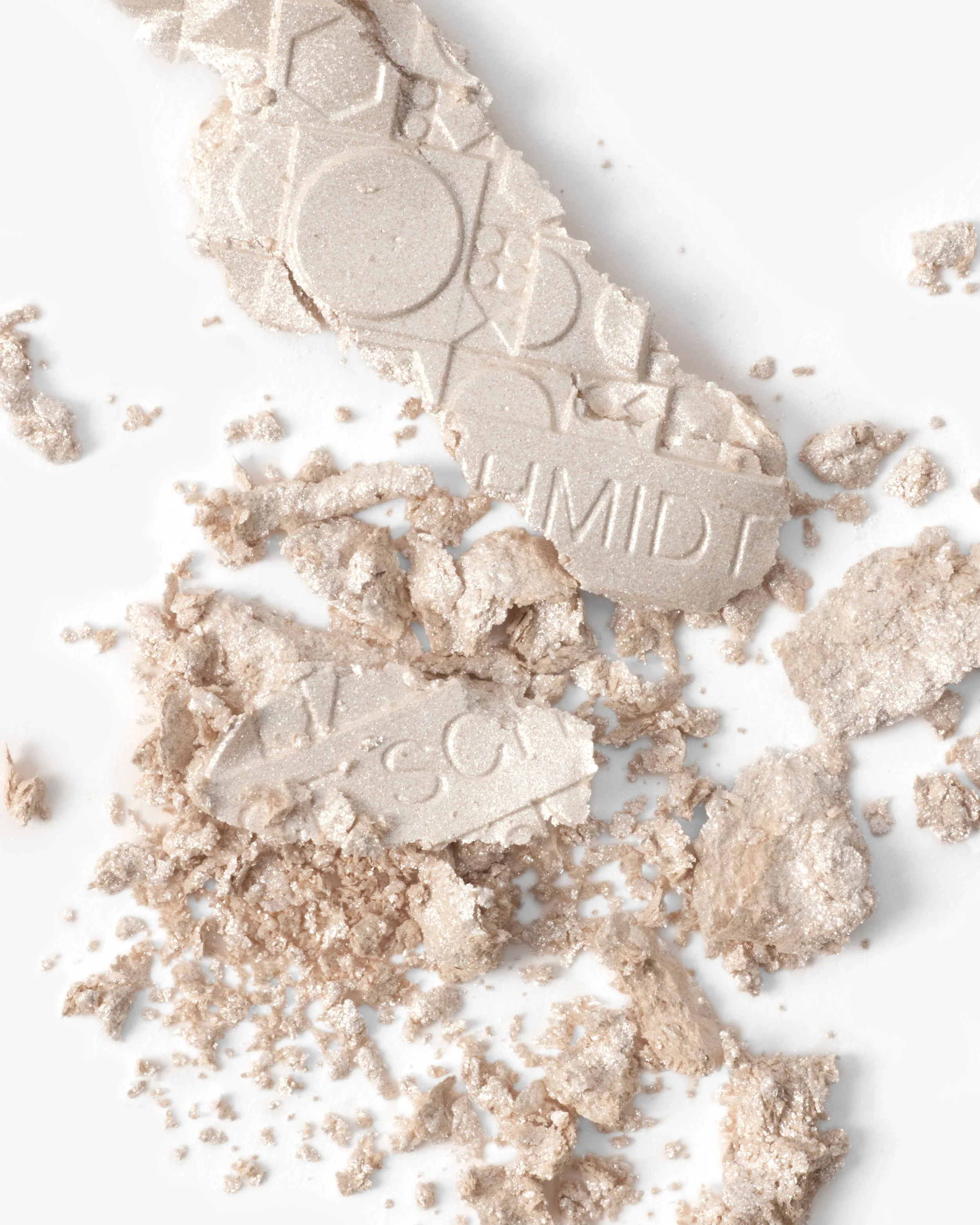Broken light beige makeup or cosmetic bronzer powder with embossed design and the word 'MILD' on a white surface.