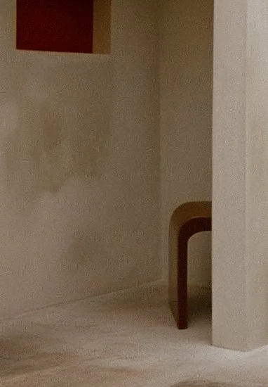 A corner of a room with a beige wall, a small wooden table, and a doorway leading to another room.