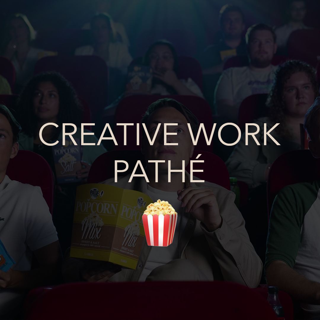 People in a theater watching a movie, with some holding popcorn and drinks, as the lights dim.